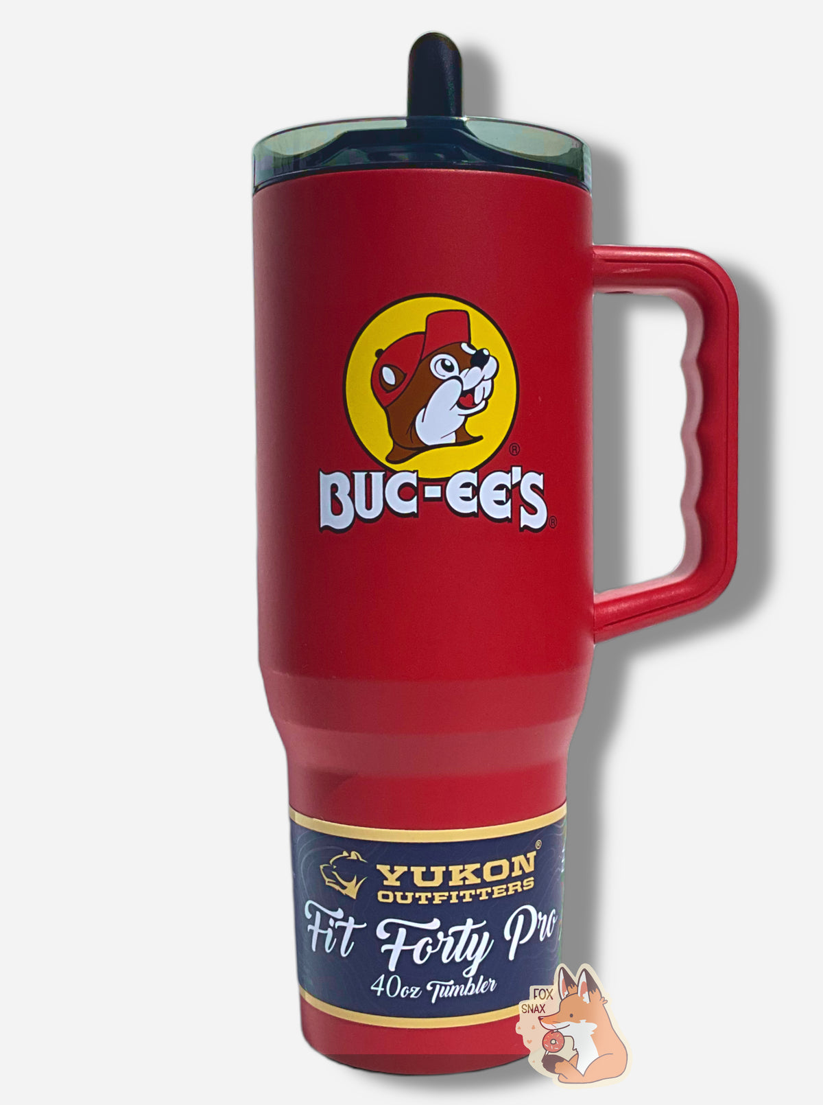A picture of a tall, red, sorta skinny tumbler, with a big picture of Buc-ee The Beaver on it, framed in a large yellow circle. The surface is smooth and red, as it is red paint covering stainless steel. The handle and top are plastic - the handle red, the top dark but clear. A small black 'sippable' straw can be seen poking up from the top of the lid. A paper wrapper around the bottom reads: Yukon Outfitters. Fit Forty Pro 40 oz Tumbler.