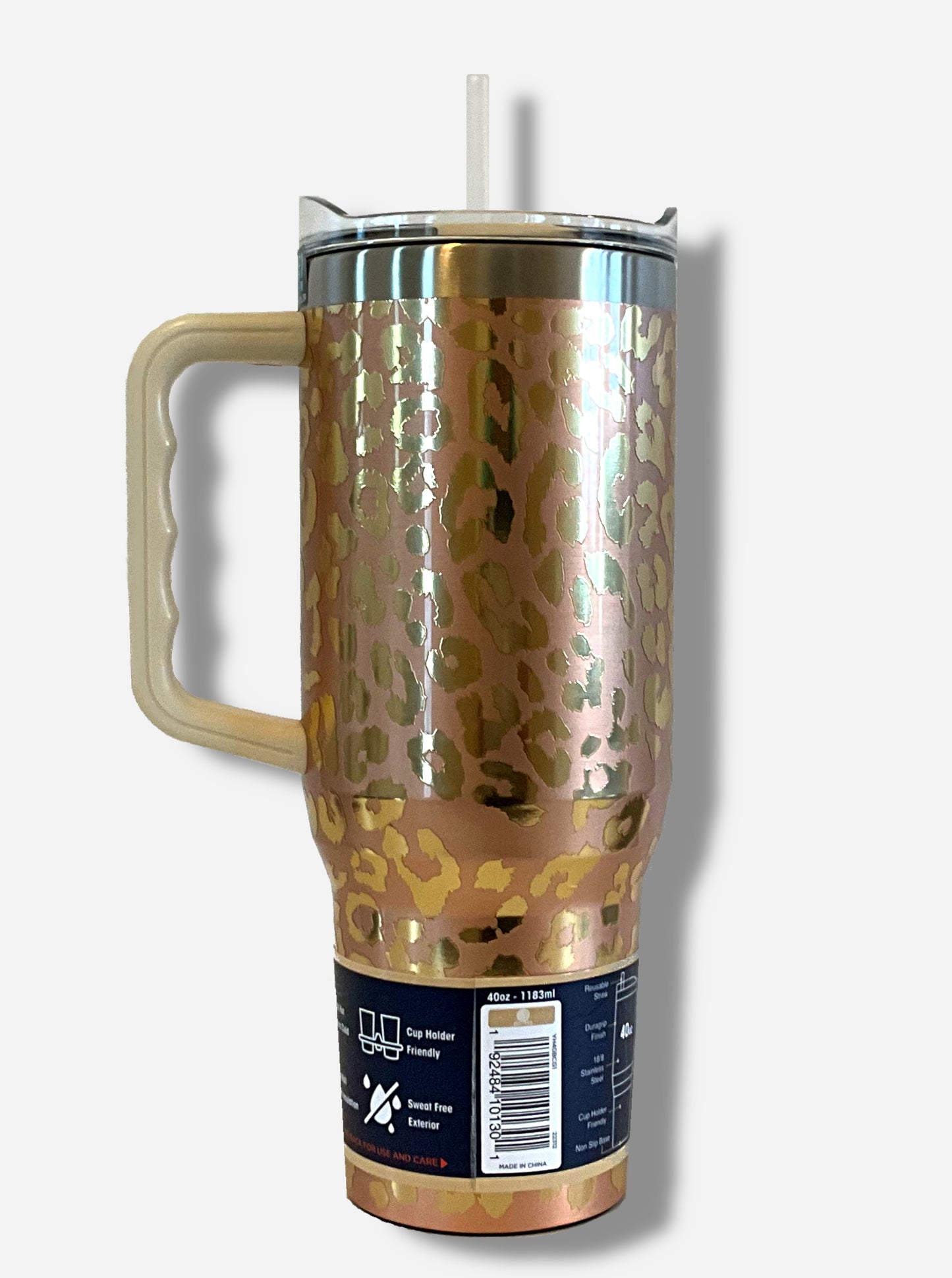 A picture of the back of a tall, gold, sorta skinny tumbler. The surface is a leopard print, as it is gold paint covering stainless steel. The handle, top, and straw are plastic. The top of the mug is lined with a stainless steel band. A paper wrapper around the bottom has a diagram that reads 40 oz, next to the barcode.