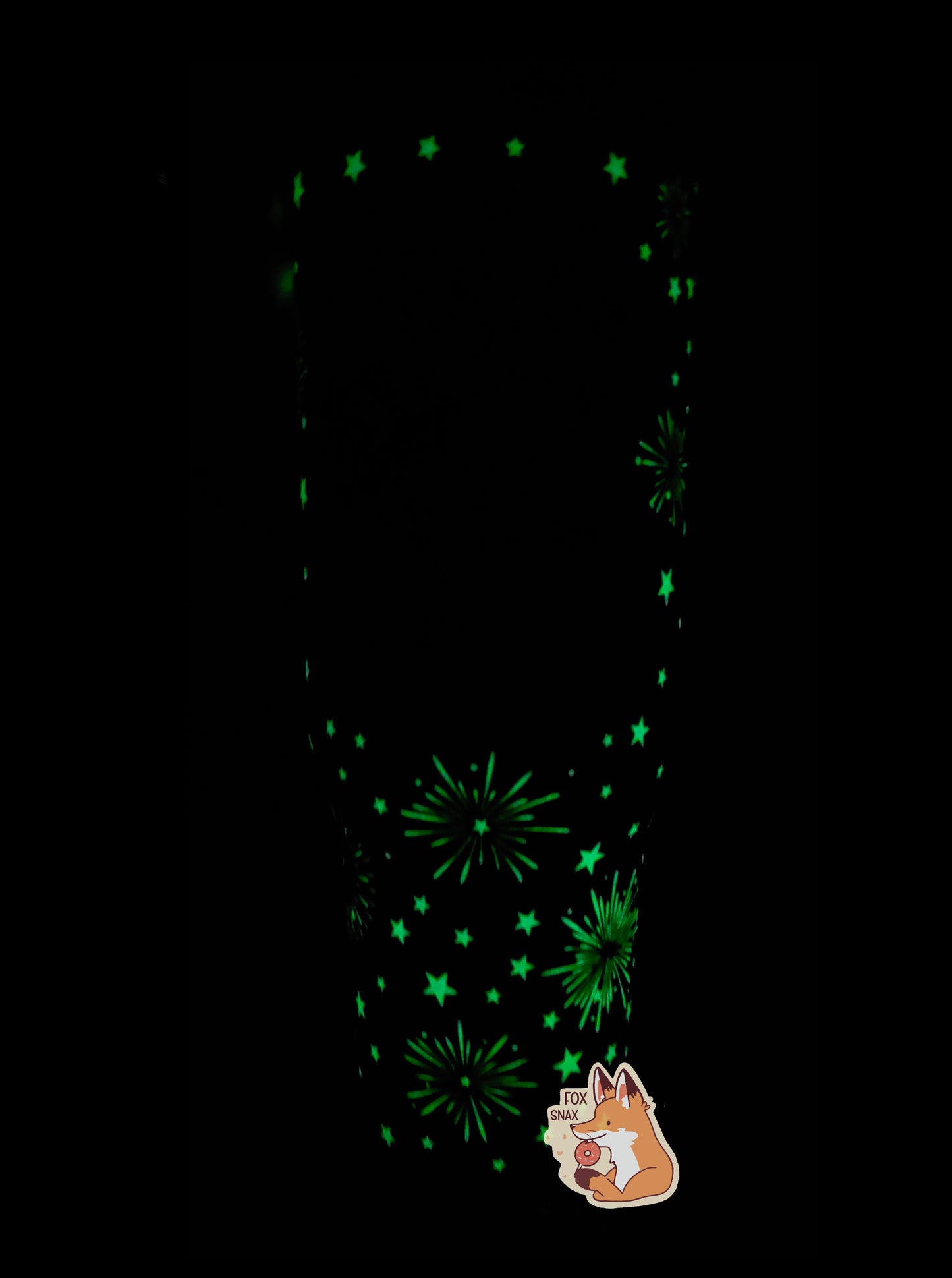 A picture of a tall, sorta skinny tumbler. The fireworks and stars that normally show in white are instead in fluorescent bright green, as it is a glow in the dark mug. The mug's surface shows glowing five-pointed stars of different sizes, framing exploding fireworks. The lid and handle cannot be seen very well in the picture because they do not glow in the dark.