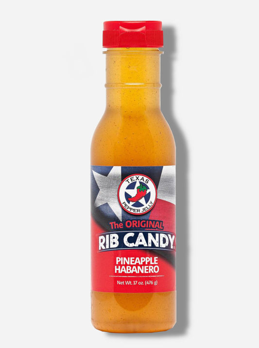 A picture of a plastic bottle of Texas Pepper Jelly's "The Original Rib Candy", Pineapple Habanero flavor.  The bottle is cylindrical and clear & the top is covered by a plastic red flip top.  The label reads: THE ORIGINAL RIB CANDY PINEAPPLE  HABANERO, NET WT 17 OZ in red and white text.  Behind the text is the Texas flag in red, white, and blue.  Inside the bottle is a orange-yellow fluid, with air bubbles suspended in the fluid.