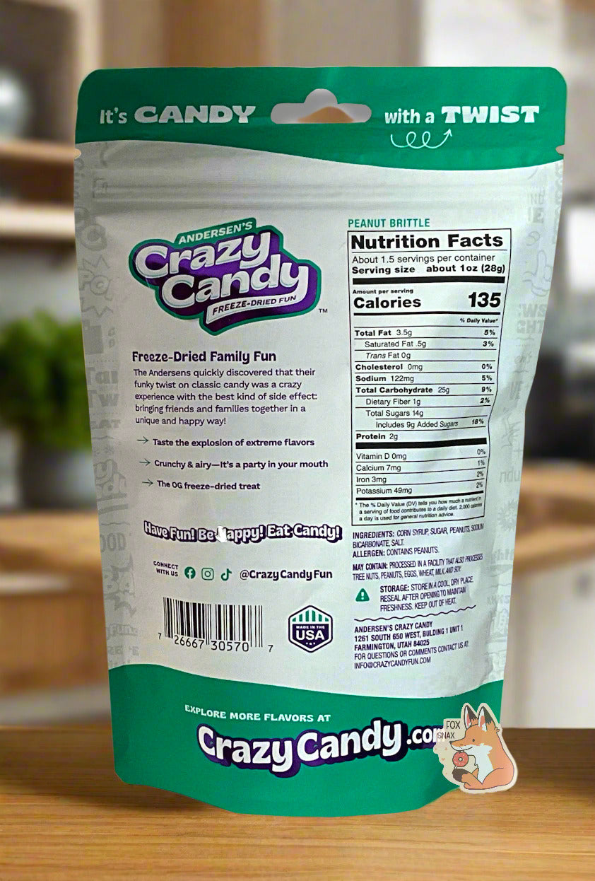 The back of a large bag of Andersen's Crazy Candy Peanut Brittle. The bag reads: Freeze Dried Family Fun. The Andersens quickly discovered that their funky twist on classic candy was a crazy experience with the best kind of side effect: bringing friends and families together in a unique and happy way! The bag is sitting in a pretty, wood-paneled kitchen, on a light wood countertop.