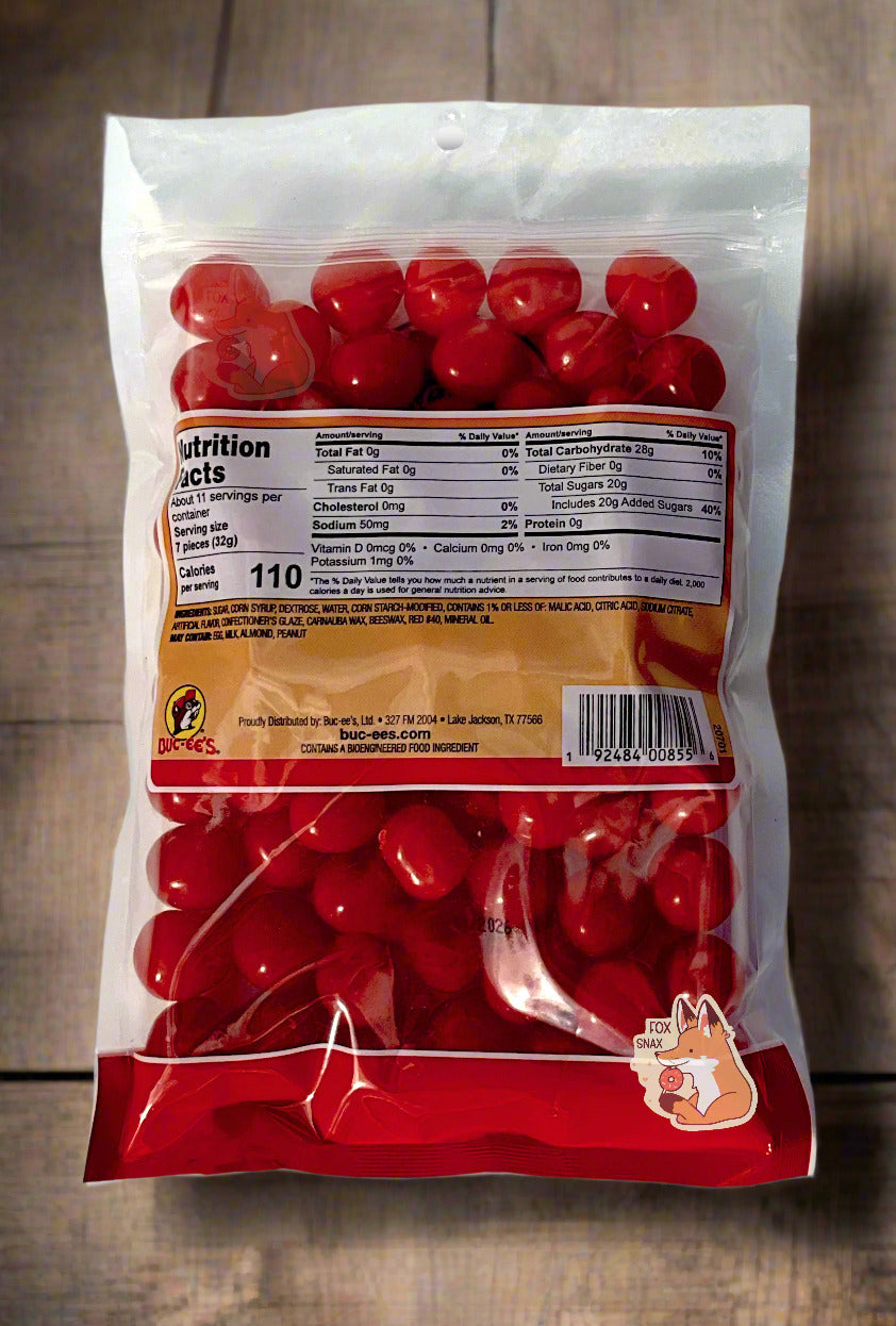 A picture of the back of a clear resealable bag of Buc-ee's Cherry Sours, which are bright red, sour and sweet spherical candies. The background is of a wood table.