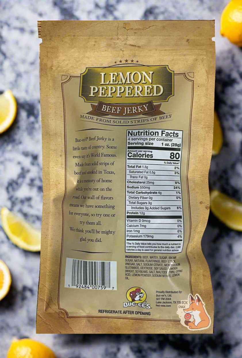 A picture of the back of a tan plastic bag of Buc-ee's Lemon Pepper Beef Jerky. The green label underneath reads 'Buc-ee's Beef Jerky is a little taste of country. Some even say it's World Famous. Made from solid strips of beef and smoked in Texas, it is a memory of home while you're out on the road. Our wall of flavors means we have something for everyone, so try one or try them all. We think you'll be mighty glad you did.' The bag is sitting on a white and black marble slab;lemon slices surround it.