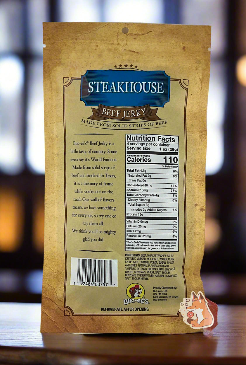 A picture of the back of a tan plastic bag of Buc-ee's Steakhouse Beef Jerky. The label underneath reads 'Buc-ee's Beef Jerky is a little taste of country. Some even say it's World Famous. Made from solid strips of beef and smoked in Texas, it is a memory of home while you're out on the road. Our wall of flavors means we have something for everyone, so try one or try them all. We think you'll be mighty glad you did.' The background shows the a steakhouse bar/restaurant with lots of dark wood.