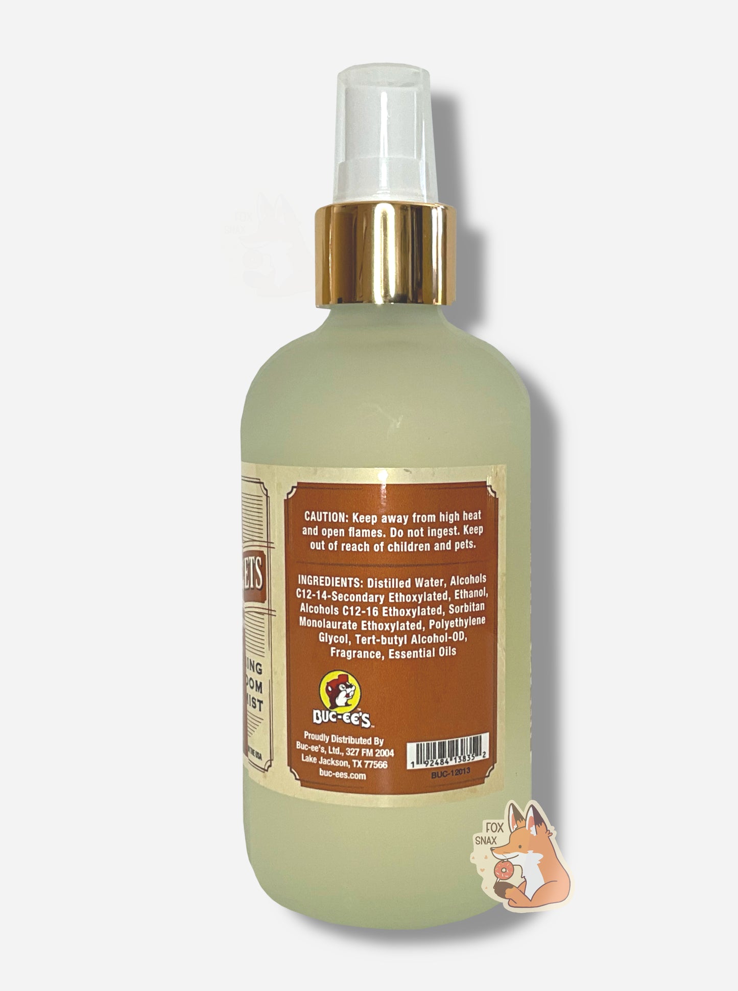 Left side of spray bottle of Buc-ee's Beaver Nuggets Freshening Room Mist on a white background. The bottle is frosted glass with a white sprayer and gold label. The label reads CAUTION: Keep away from high heat and open flames. Do not ingest. Keep out of reach of children and pets.