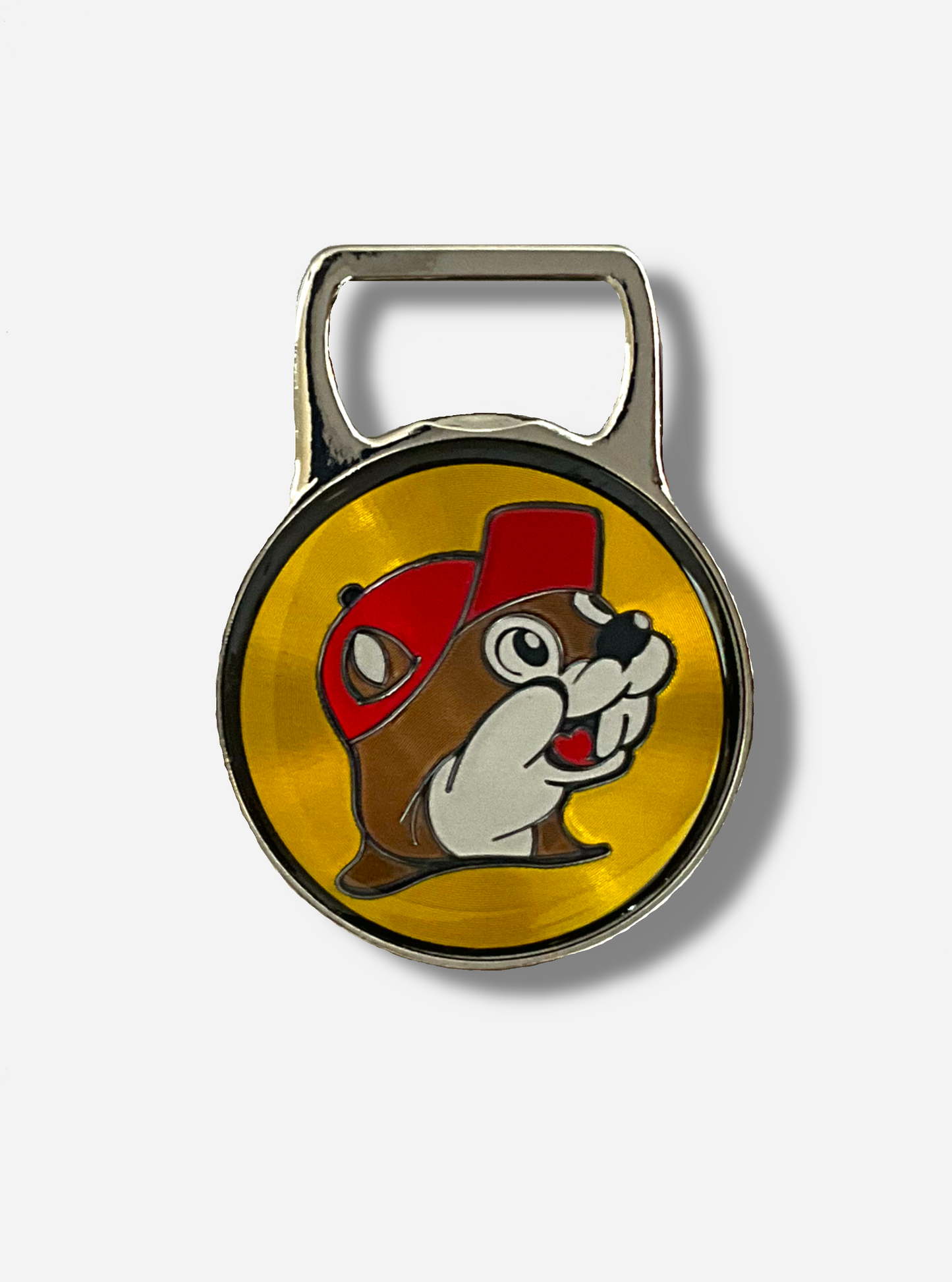 A picture of the front of a metallic bottle opener. The top of the opener is a grey metal and shaped to open bottles. The bottom of the opener is a circle, which contains the Buc-ee's logo - a cheerful beaver wearing a red ball cap, in front of a yellow circle logo.