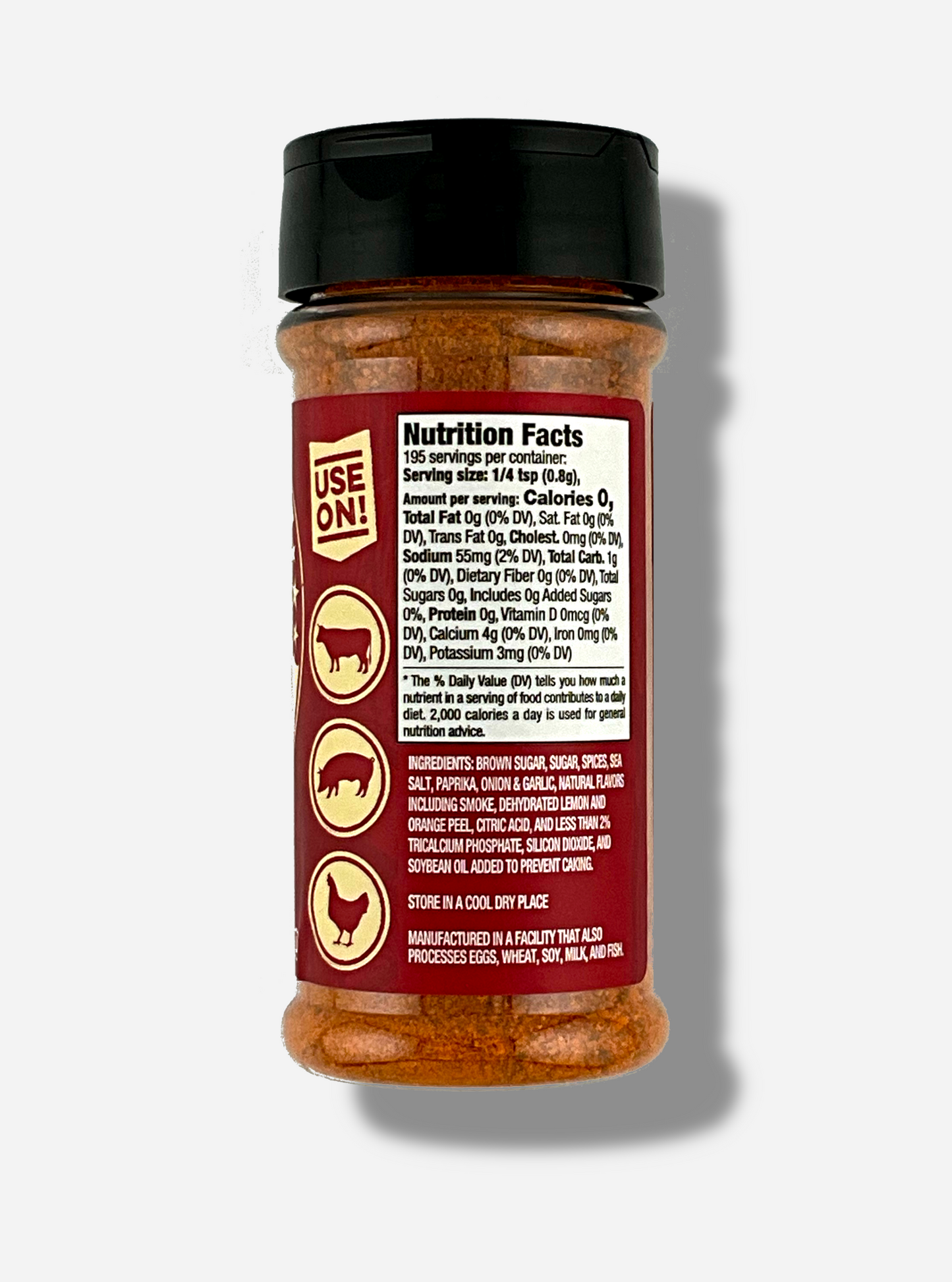 A picture of the back of a container of Texas Round Up BBQ Rub. The container has a black plastic flip lid, and a clear plastic body. The spices inside appear red/orange and black. The red label reads USE ON!, and beneath that, there is an outline of a cow, a pig, and a chicken.