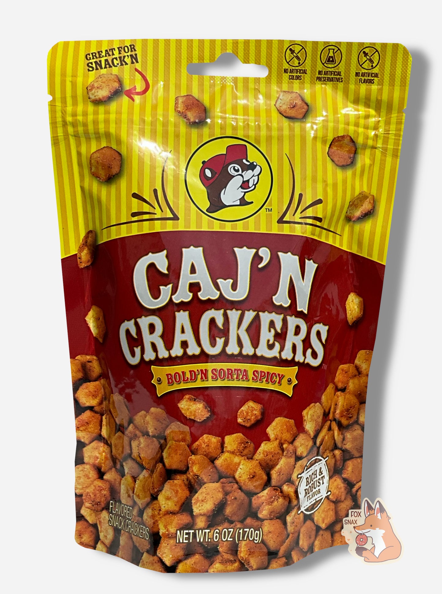 A picture of a metallic bag of Buc-ee's Caj'N Crackers and Bold'N Sorta Spicy. The logo is a dark red background on white text; a large number of reddish, savory-looking hexagonal oyster crackers are shown beneath it. At the top is a picture of the logo of Buc-ee The Beaver, and it reads GREAT FOR SNACK'N, NO ARTIFICIAL COLORS, NO ARTIFICIAL PRESERVATIVES, NO ARTIFICIAL FLAVORS and RICH AND ROBUST FLAVOR