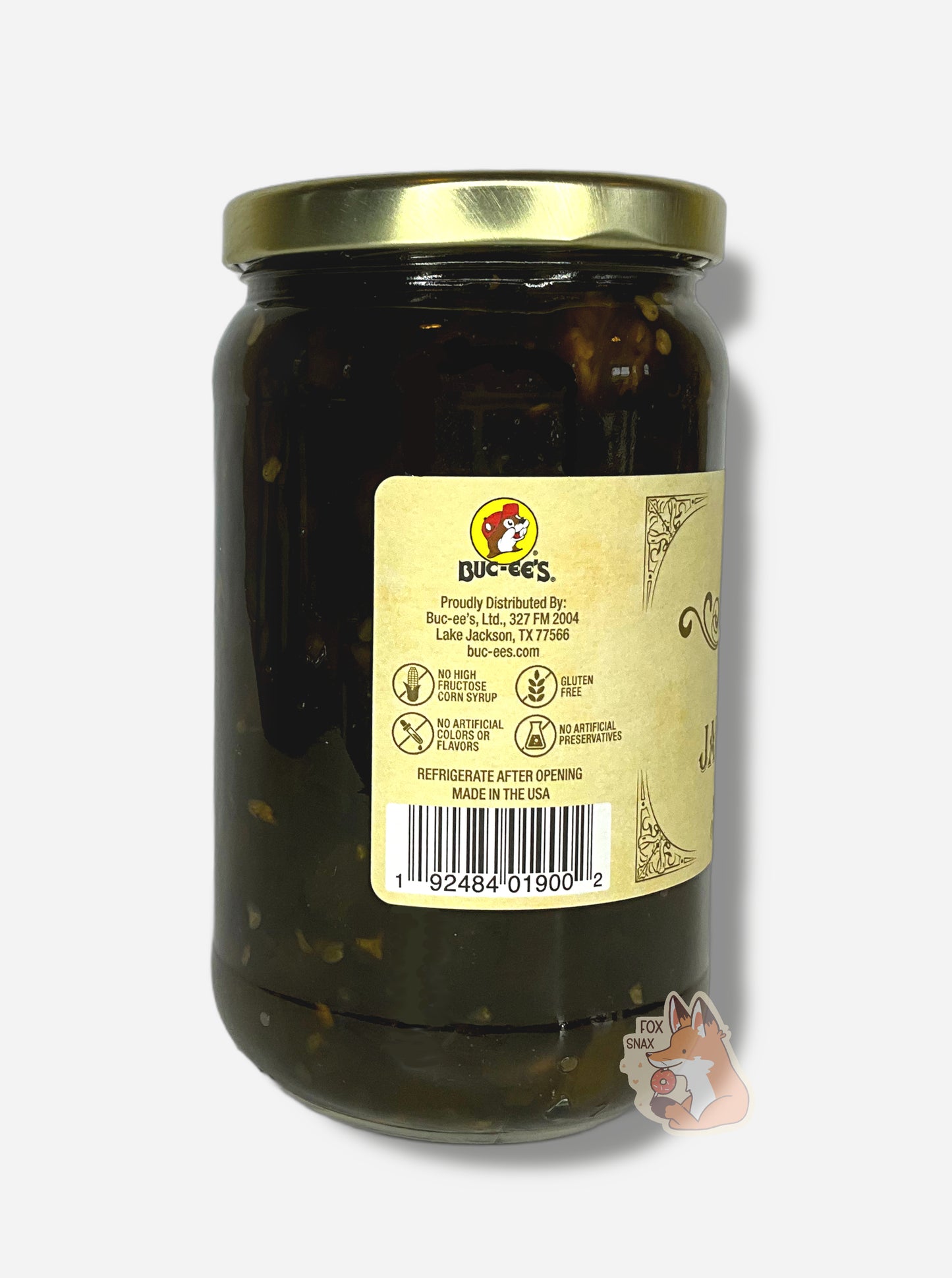A picture of the left side of a glass jar of Buc-ee's Candied Jalapeños - the label is a "old-timey" sort of white/yellow with flared edges. The middle reads No High Fructose Corn Syrup, No Artificial Colors Or Flavors, Gluten Free, No Artificial Preservatives. In the jar, dark green jalapeños can be seen.