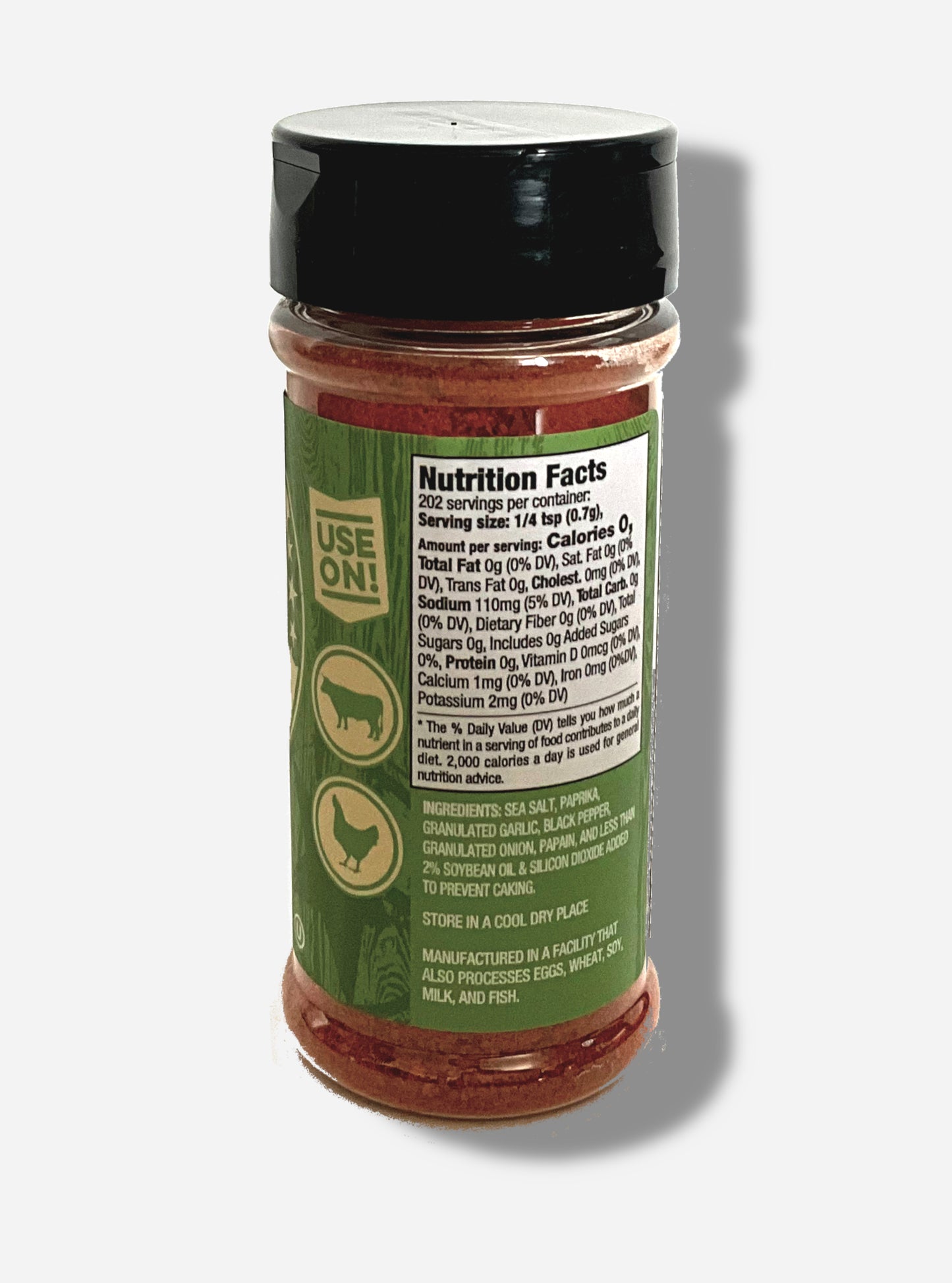 A picture of the back of a container of Texas Round Up Fajita Seasoning. The container has a black plastic flip lid, and a clear plastic body. The spices inside appear red and orange. The green label reads USE ON!, and beneath that, there is an outline of a cow and a chicken.