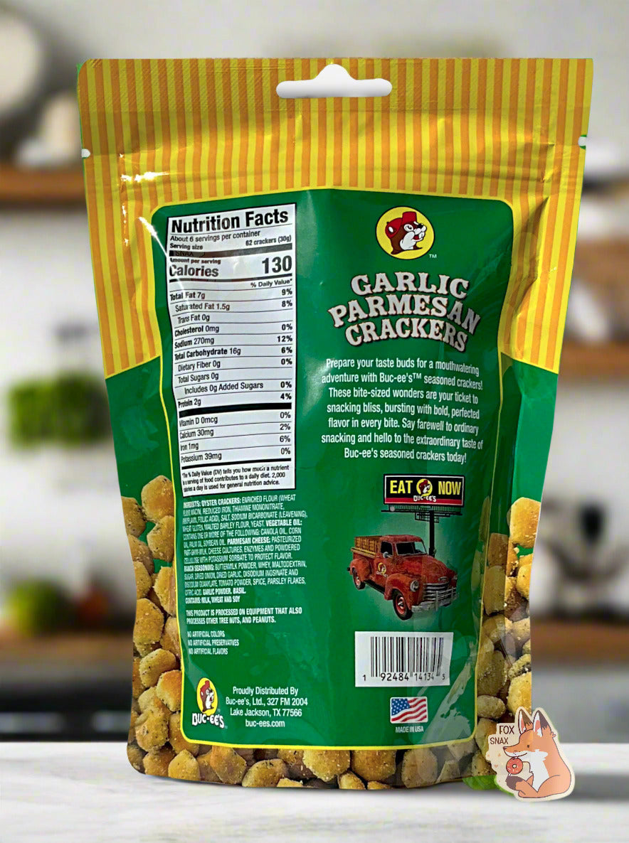 A picture of a the back of a metallic bag of Buc-ee's Garlic Parmesan Crackers. It reads "Prepare your taste buds for a mouthwatering adventure with Buc-ee's TM seasoned crackers! These bite-sized wonders are your ticket to snacking bliss, bursting with bold, perfected flavor in every bite. Say farewell to ordinary snacking and hello to the extraordinary taste of Buc-ee's seasoned crackers today!" The background shows a kitchen with grey walls; ingredients and wood shelves can be seen in the background.