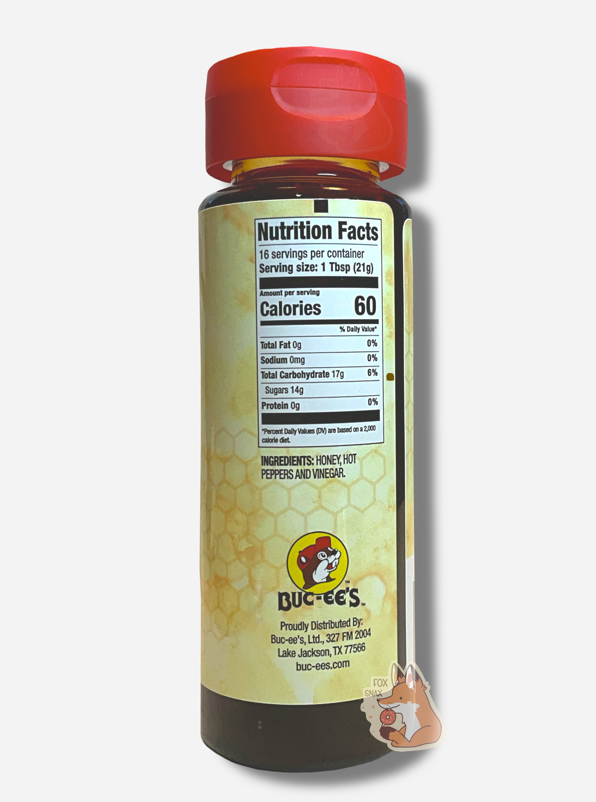 The side of a plastic bottle of Buc-ee's Hot Honey.  The top of the bottle is a plastic red flip top.  The bottom is clear plastic; the brown/yellow honey inside can be seen.  A label surrounds the bottle, which reads INGREDIENTS: HONEY, HOT PEPPERS AND VINEGAR.