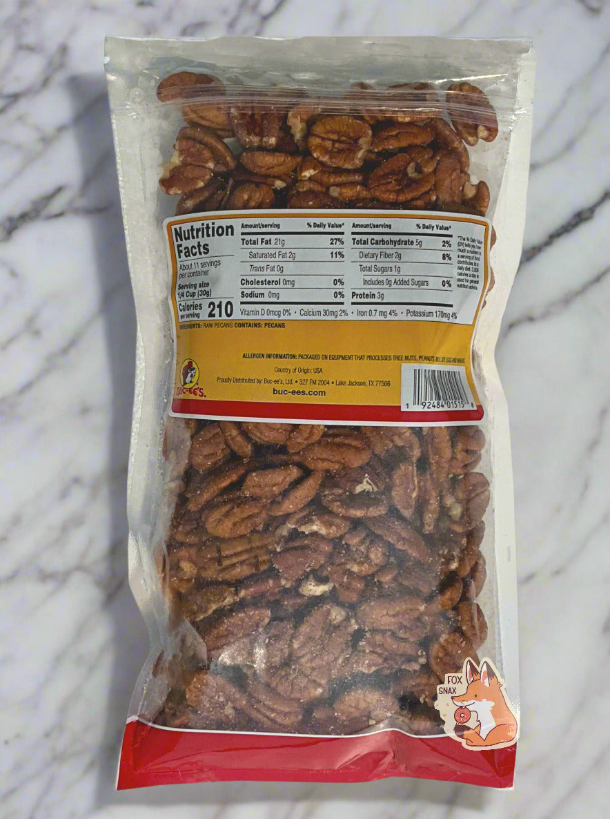 A picture of the back of a clear plastic bag of Buc-ee's Mammoth Pecans. Inside the bag are a large number of brown dried pecans. The bag is laying on a large marble slab, suitable for creation of fine baking goods.