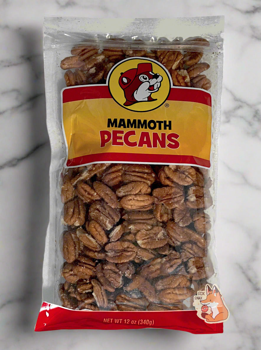 A picture of a clear plastic bag of Buc-ee's Mammoth Pecans. The Buc-ee's logo can be seen in the top center of the bag, then underneath that in black and red text, MAMMOTH PECANS. The bottom of the bag is red and reads Net Wt 12 oz. Inside the bag are a large number of large dried pecans. The bag is laying on a large marble slab, suitable for creation of fine baking goods.
