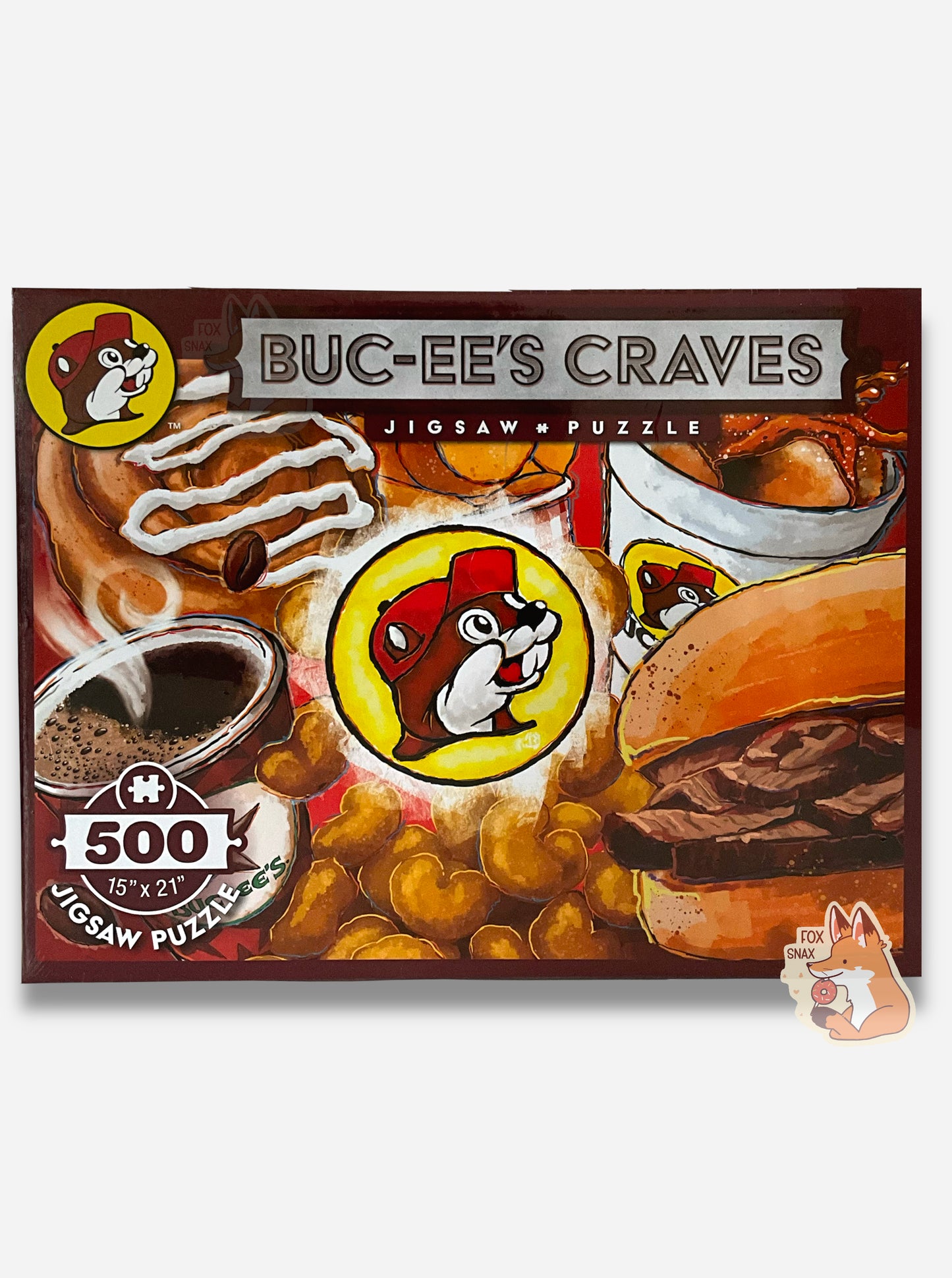 A picture of a jigsaw puzzle. The top of the puzzle reads BUC-EE'S CRAVES, then JIGSAW PUZZLE in smaller font. The lower left reads 500 (pieces), 19 x 21. The top left has the Buc-ee's logo. The puzzle itself is a collage of different painted items: a beaver tail pastry, beaver chips in a cup, a icy beverage, a fresk brisket sandwich, beaver nuggets, and a hot coffee.
