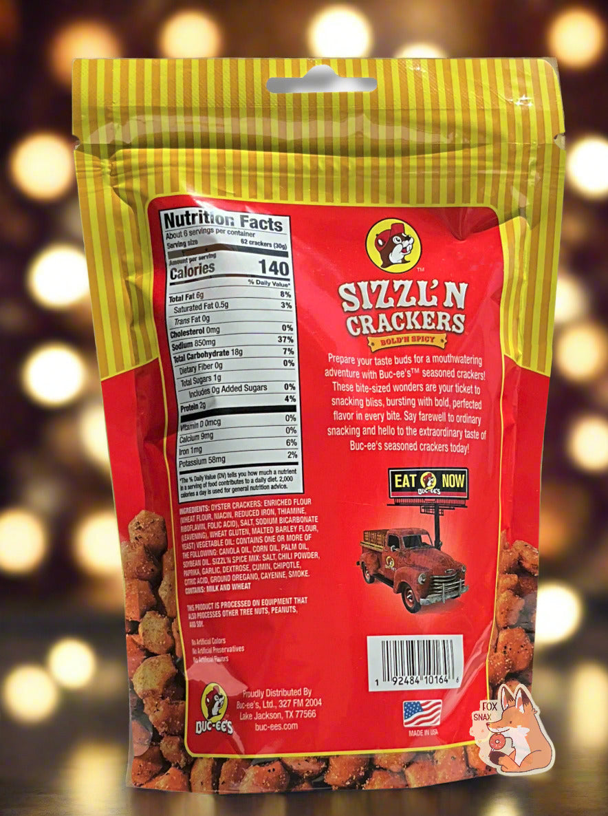 A picture of a the back of a metallic bag of Buc-ee's Sizzl'n Crackers. It reads "Prepare your taste buds for a mouthwatering adventure with Buc-ee's TM seasoned crackers! These bite-sized wonders are your ticket to snacking bliss, bursting with bold, perfected flavor in every bite. Say farewell to ordinary snacking and hello to the extraordinary taste of Buc-ee's seasoned crackers today!" The background shows many bright lights framing the bag.