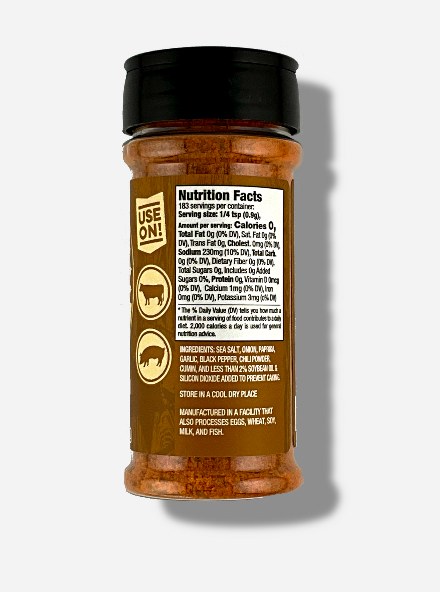 A picture of the back of a container of Texas Round Up Steak Seasoning. The container has a black plastic flip lid, and a clear plastic body. The spices inside appear orange and grey. The tan label reads USE ON!, and beneath that, there is an outline of a cow and a pig.