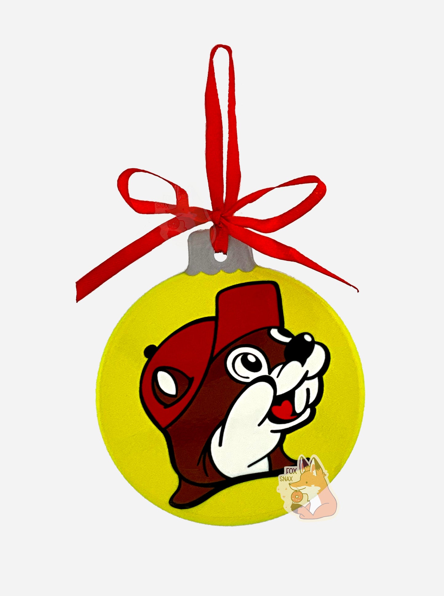 A picture of the front of a ceramic, mostly round ornament, with a red ribbon at the top to hang it on a tree. The ornament has a picture of Buc-ee The Beaver on it, but Buc-ee is wearing a Santa hat instead of his usual red ball cap. The background of the ornament is cheery and multicolored with plaid stripes. Several abstract snowflakes in white dot the plaid background. The Santa hat pokes out slightly from the left rim of the ornament. The ornament is laid against a pure white background.