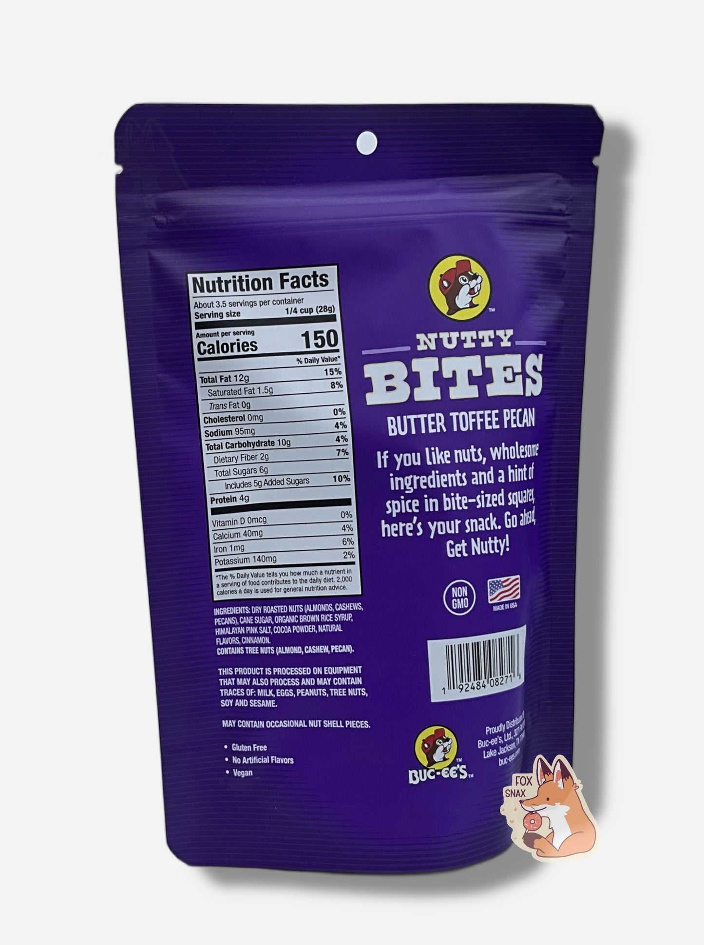 A picture of the back of a white and purple bag of Buc-ee's Butter Toffee Pecan Nutty Bites. The Buc-ee's logo can be seen in the top right of the bag, then under that, NUTTY BITES, then BUTTER TOFFEE PECAN, then "If you like nuts, wholesome ingredients and a hint of spice in bite-sized squares, here's your snack. Go ahead and Get Nutty!" Nutrition facts and ingredients are listed as well.