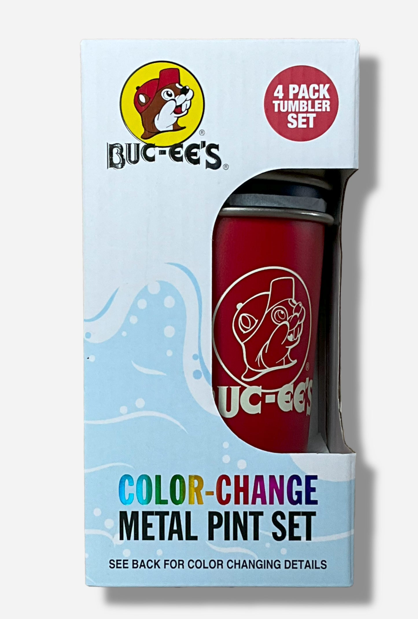A picture of a small, light blue box that reads (on the bottom) COLOR-CHANGE METAL PINT SET, then underneath that, SEE BACK FOR COLOR CHANGING DETAILS. On the top left of the box is the Buc-ee's logo, then next to it, white text in a red circle that reads 4 PACK TUMBLER SET. On the middle right is a cutout from the box, where one of the tumblers- the red one with white text - can be seen. The text and logo in white is of the Buc-ee's logo.