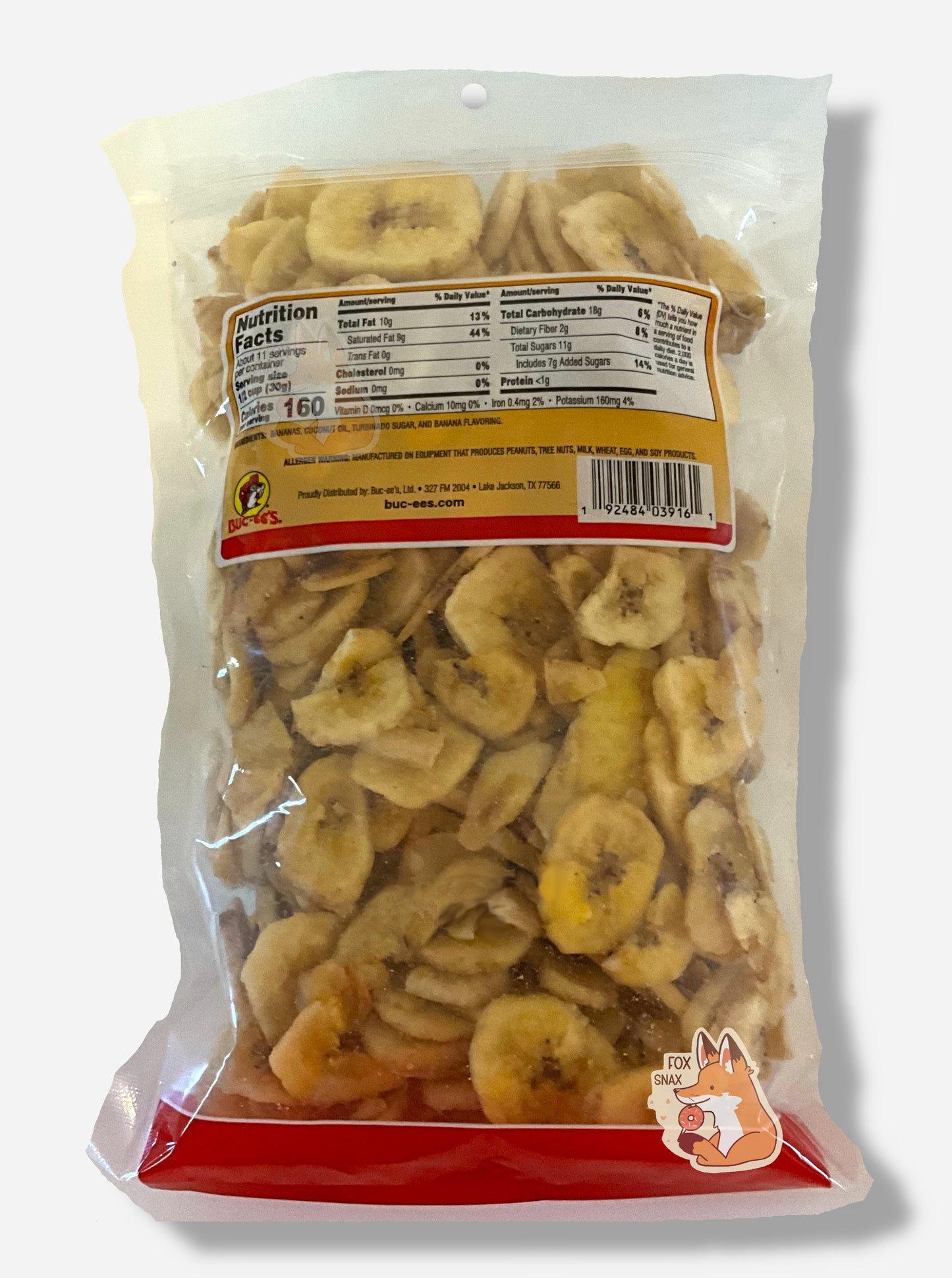 The back of a clear bag of Buc-ee's Sweetened Dried Banana Chips. The bottom of the bag has a red stripe. The middle of the bag is clear, and has a large amount of skinny circular yellow dried banana chips.