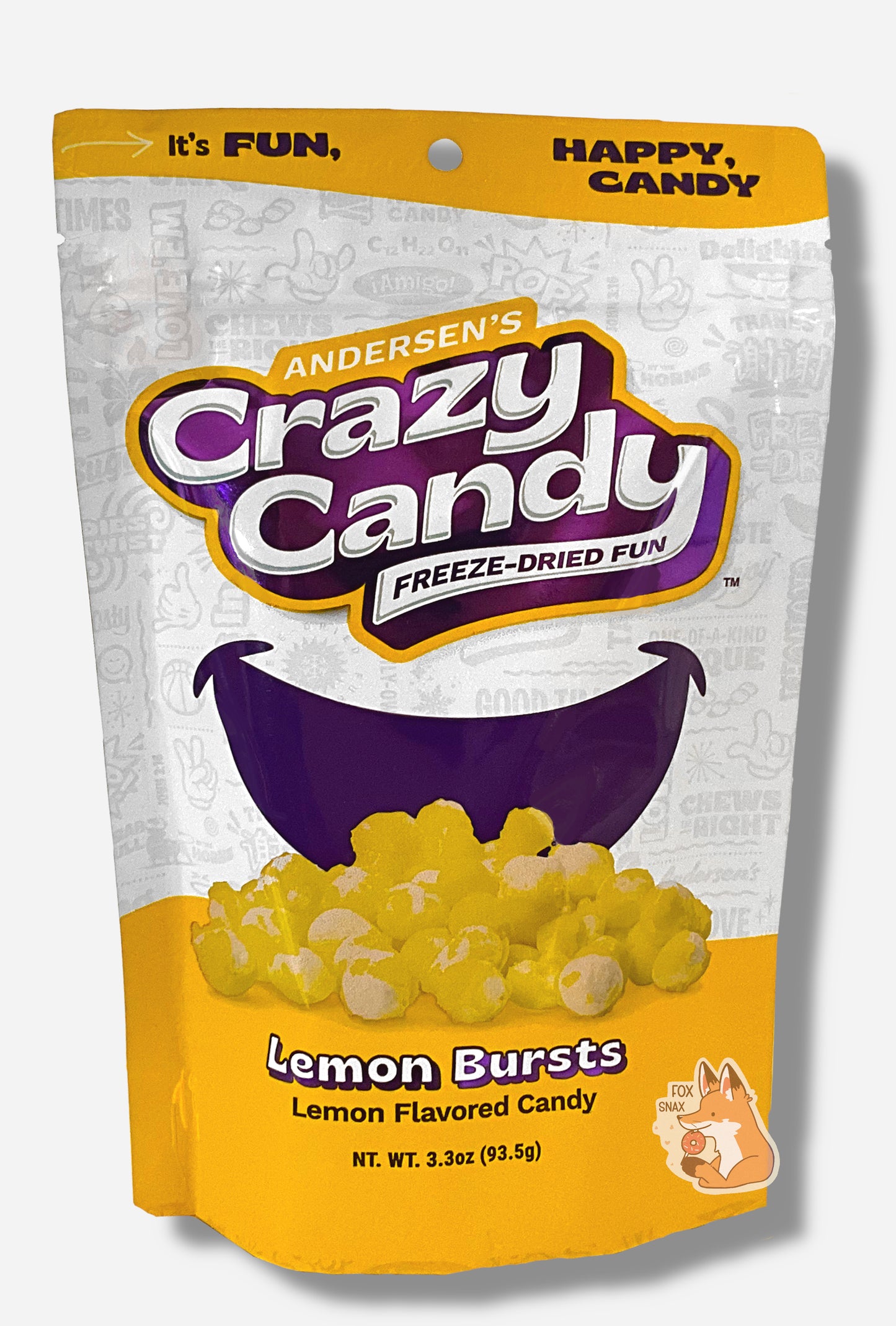 A large bag of Andersen's Lemon Bursts. The front of the bag also says Lemon, Net Weight 3.3 oz. It's Fun, Happy, Candy. The top and bottom of the bag are yellow, and the background is a large purple smile against a white background.