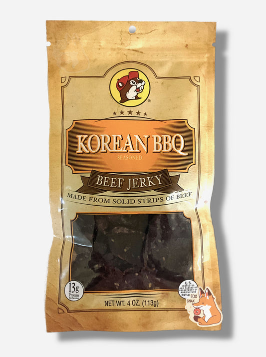 A picture of the front of a tan plastic bag of Buc-ee's Korean BBQ Beef Jerky.  The logo is in orange with white text.The label underneath reads 'Made From Solid Strips Of Beef'.A small window on the bottom of the bag shows the dark brown dried jerky inside.  The bag has a picture of Buc-ee the Beaver on it.