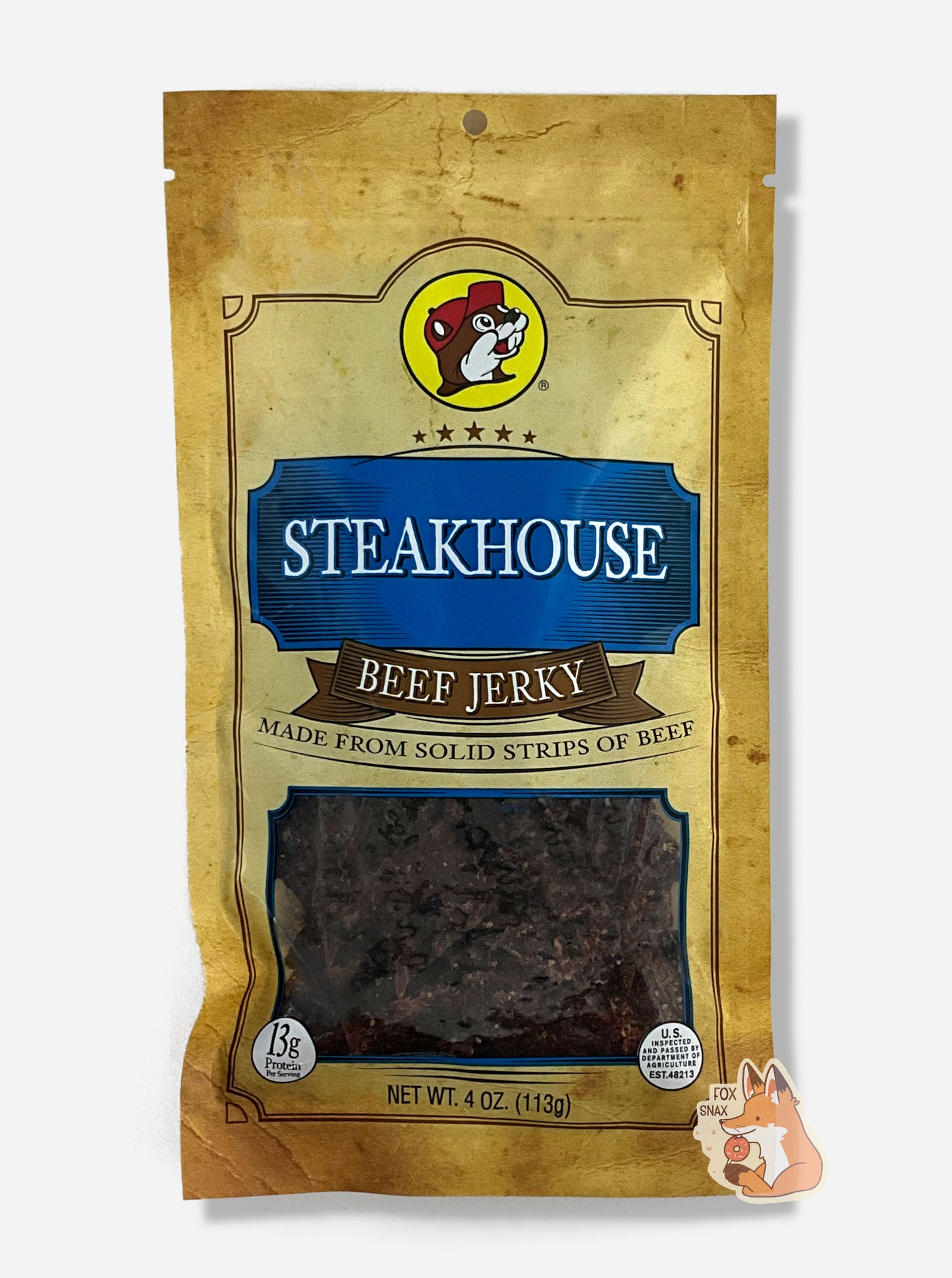 A picture of the front of a tan plastic bag of Buc-ee's Steakhouse Beef Jerky. The logo is in dark blue with white text. The label underneath reads 'Made From Solid Strips Of Beef'.A small window on the bottom of the bag shows the dark brown/red dried jerky inside. The bag has a picture of Buc-ee the Beaver on it.