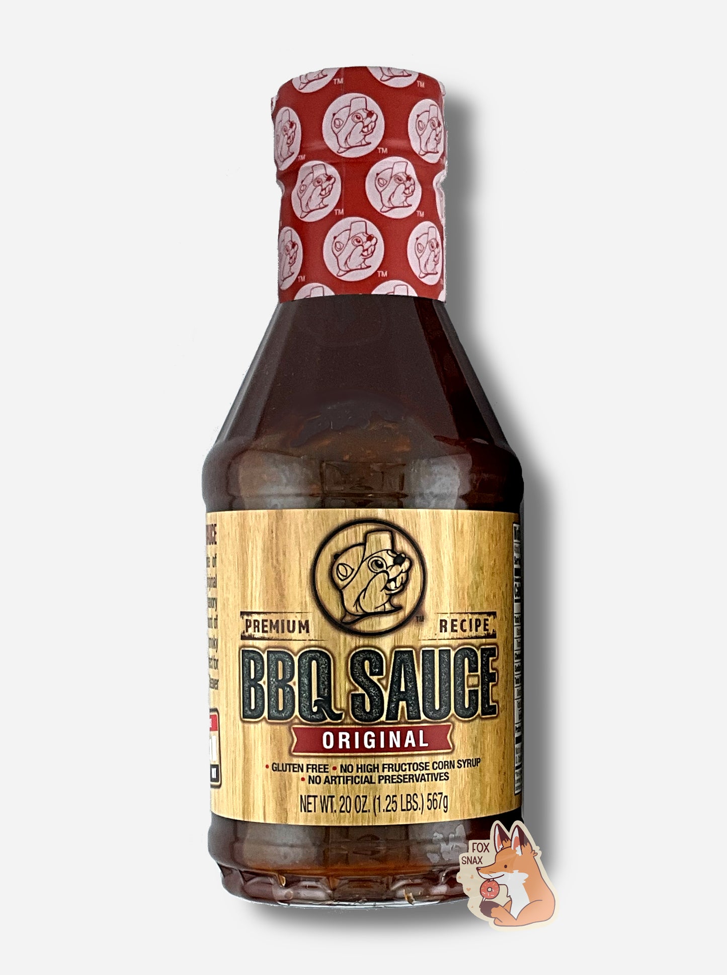 A plastic bottle of Buc-ee's Premium Recipe BBQ Sauce, Original. The top of the bottle is sealed with a plastic wrap in red and white, dotted with Buc-ee's logos. The BBQ label is a woodgrain, with a seared Buc-ee logo in the middle. The rest of the bottle is clear, and dark red-brown bbq sauce can be seen. The label reads: Gluten Free, No High Fructose Syrup, No Artificial Preservatives.