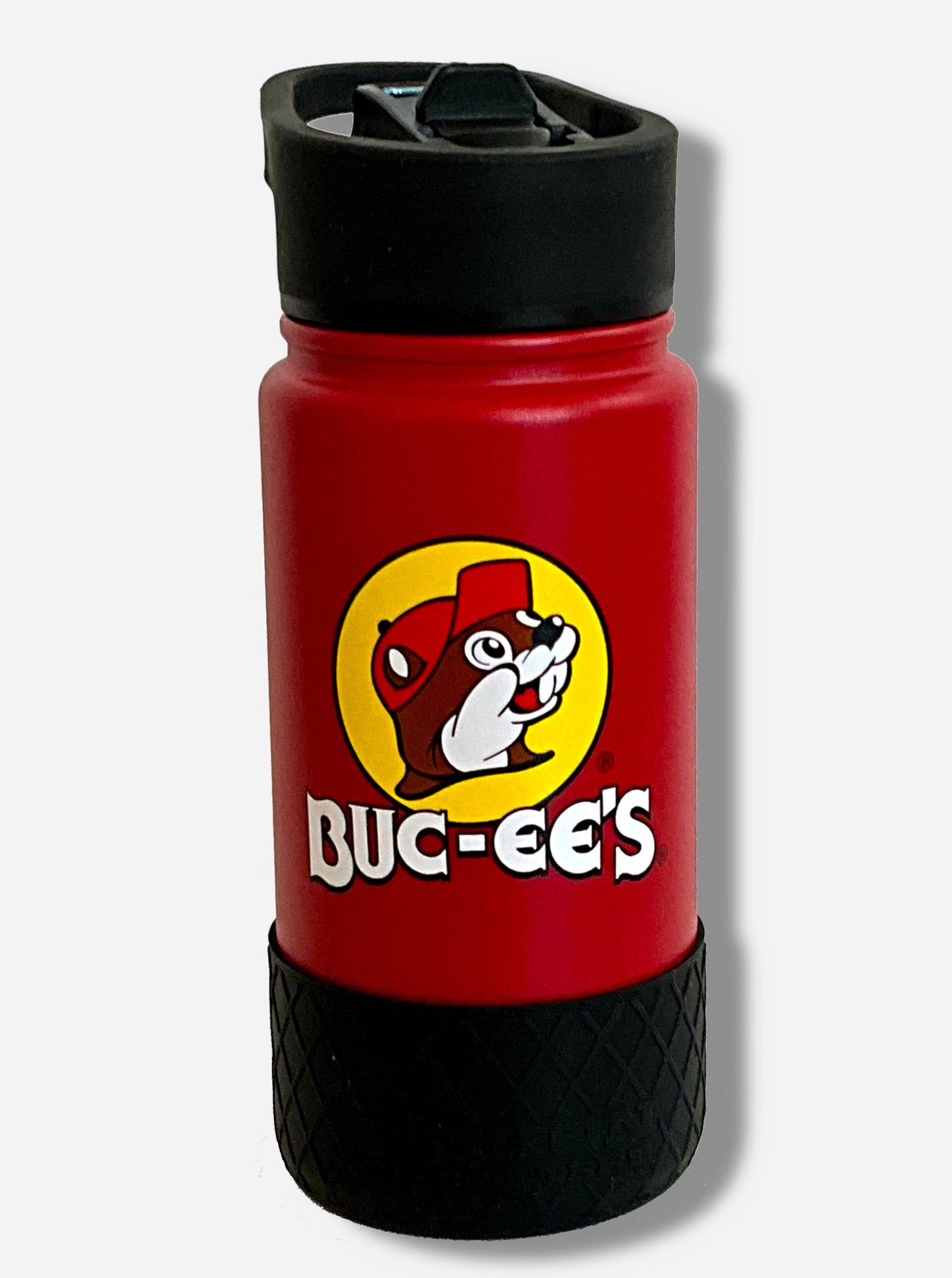 A picture of a small red cylindrical water bottle, with a giant Buc-ee The Beaver logo on the side; he's framed by a yellow background, and is wearing a red ball cap. The surface of the water bottle is red paint over metal. The top of the water bottle features a black plastic handle with a flipstraw lid. The bottom features a black plastic grippable bumper in a crosshatch pattern.