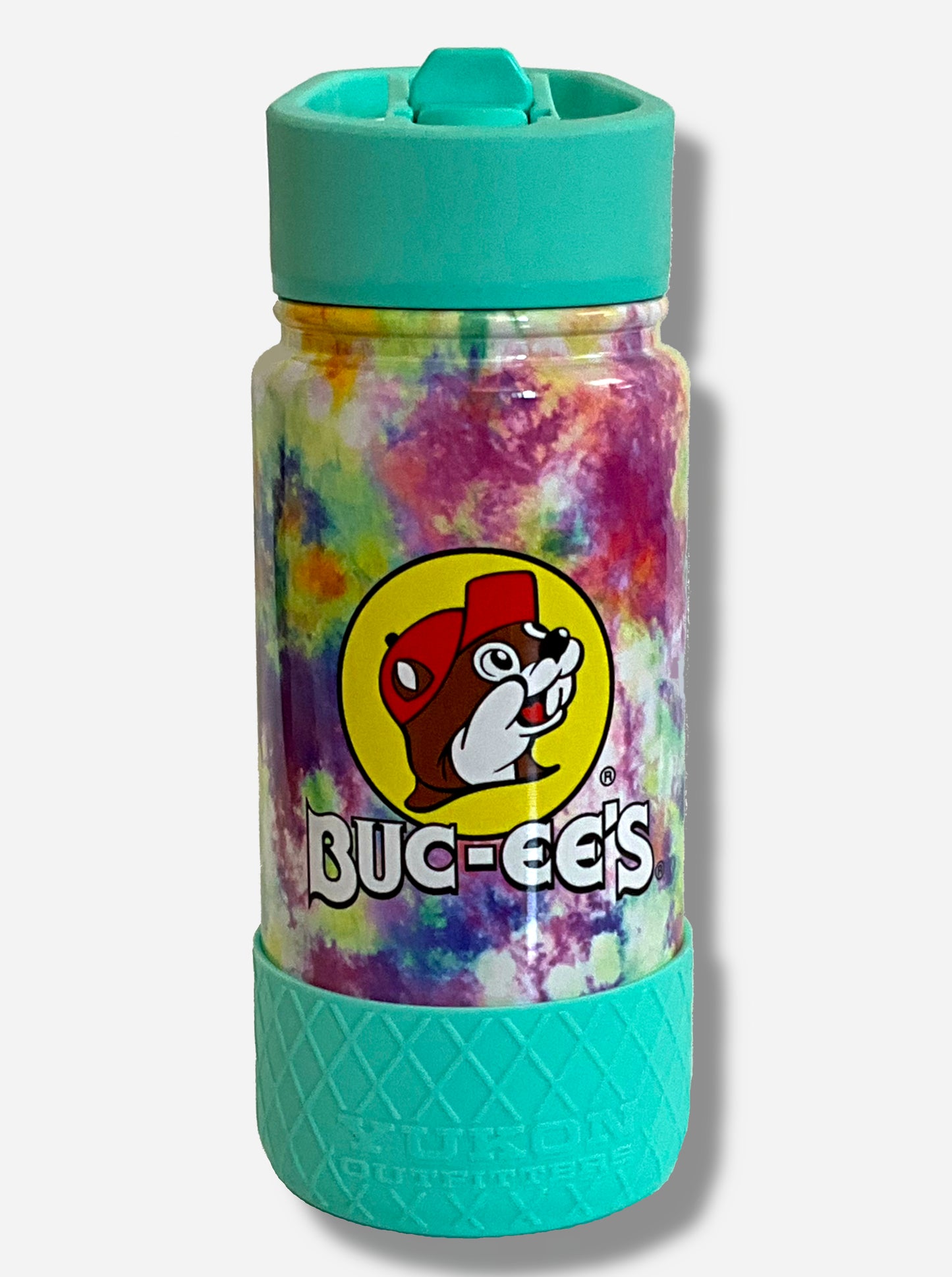 A picture of a small tie dye swirled cylindrical water bottle, with a giant Buc-ee The Beaver logo on the side; he's framed by a yellow background, and is wearing a red ball cap. The surface of the water bottle is tie dye paint over metal. The top of the water bottle features a blue plastic handle with a flipstraw lid. The bottom features a blue plastic grippable bumper in a crosshatch pattern.