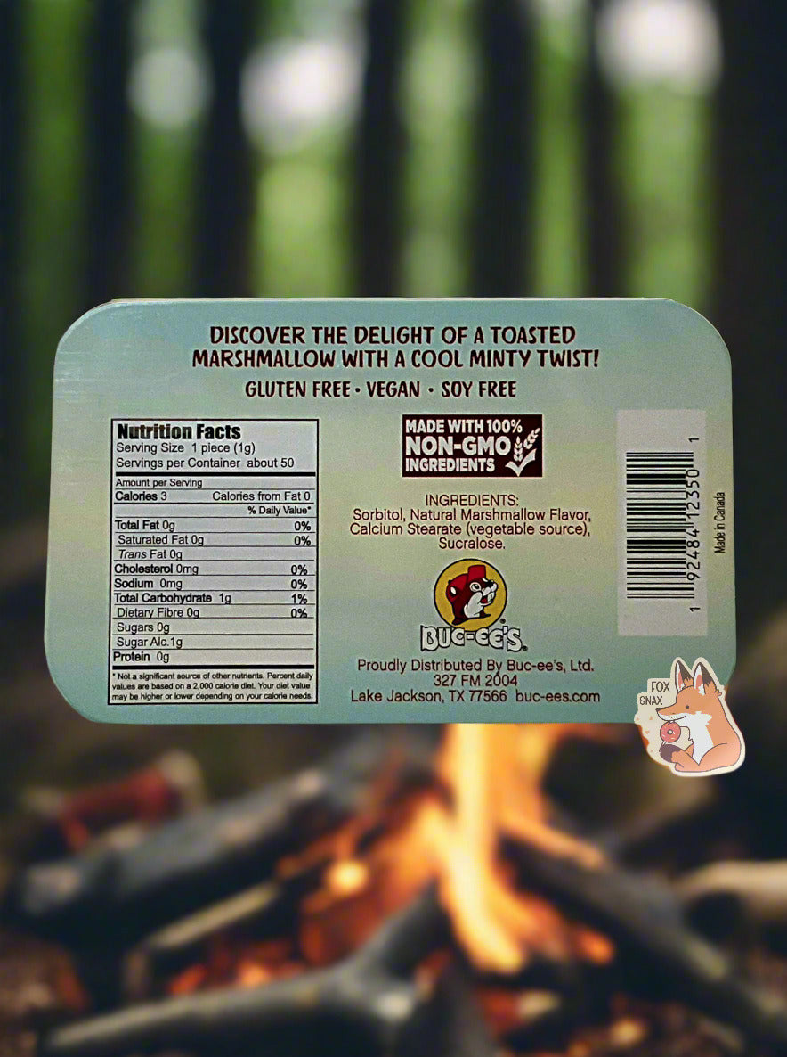 A picture of a back of a tin of Buc-ees Marshmallow Mints. The back cover is decorated with a small picture of Buc-ee The Beaver, and has the following text: Discover the delight of a toasted marshmallow with a cool minty twist! Gluten Free, Vegan, Soy Free. The background is of a pine forest; a large campfire can be seen in the background.