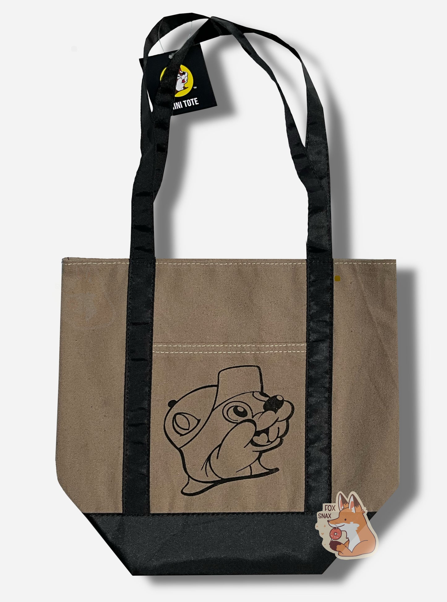 Picture of a small tote bag, with shiny black cloth straps. In the center of the bag is a black outline of Buc-ee The Beaver: a jolly beaver wearing a ballcap and a buc-toothed smile.