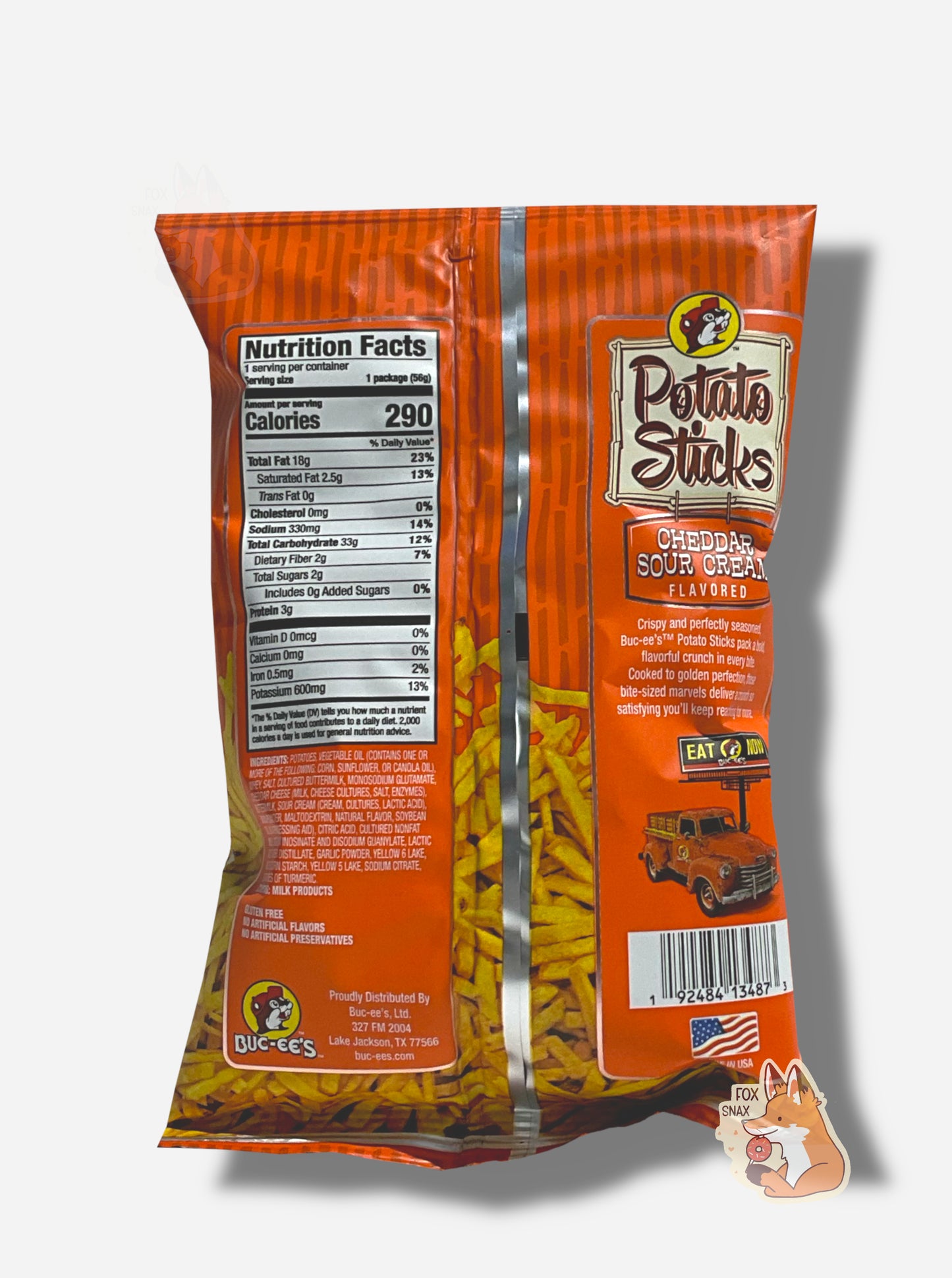 The back of a bag of Buc-ee's Cheddar Sour Cream Flavored Potato Sticks. The bag is in dark and light orange. Ingredients are listed, next to text that reads CRISPY AND PERFECTLY SEASONED, BUC-EE'S POTATO STICKS PACK A BOLD, FLAVORFUL CRUNCH IN EVERY BITE. COOKED TO GOLDEN PERFECTION, THESE BITE-SIZED MARVELS DELIVER A CRUNCH SO SATISFYING YOU'LL KEEP REACHING FOR MORE.