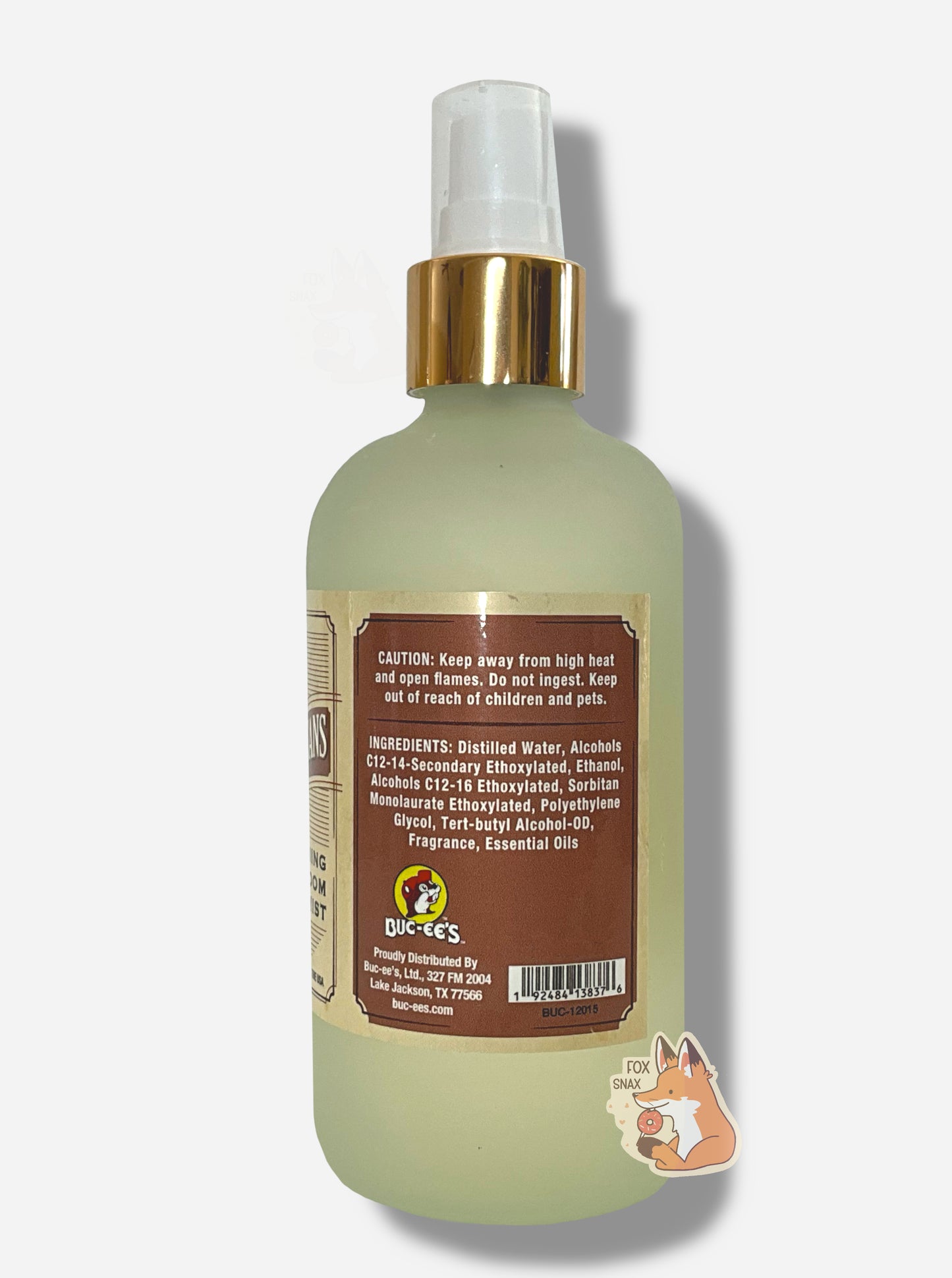 Left side of spray bottle of Buc-ee's Roasted Pecans Freshening Room Mist on a white background. The bottle is frosted glass with a white sprayer and gold label. The label reads CAUTION: Keep away from high heat and open flames. Do not ingest. Keep out of reach of children and pets.
