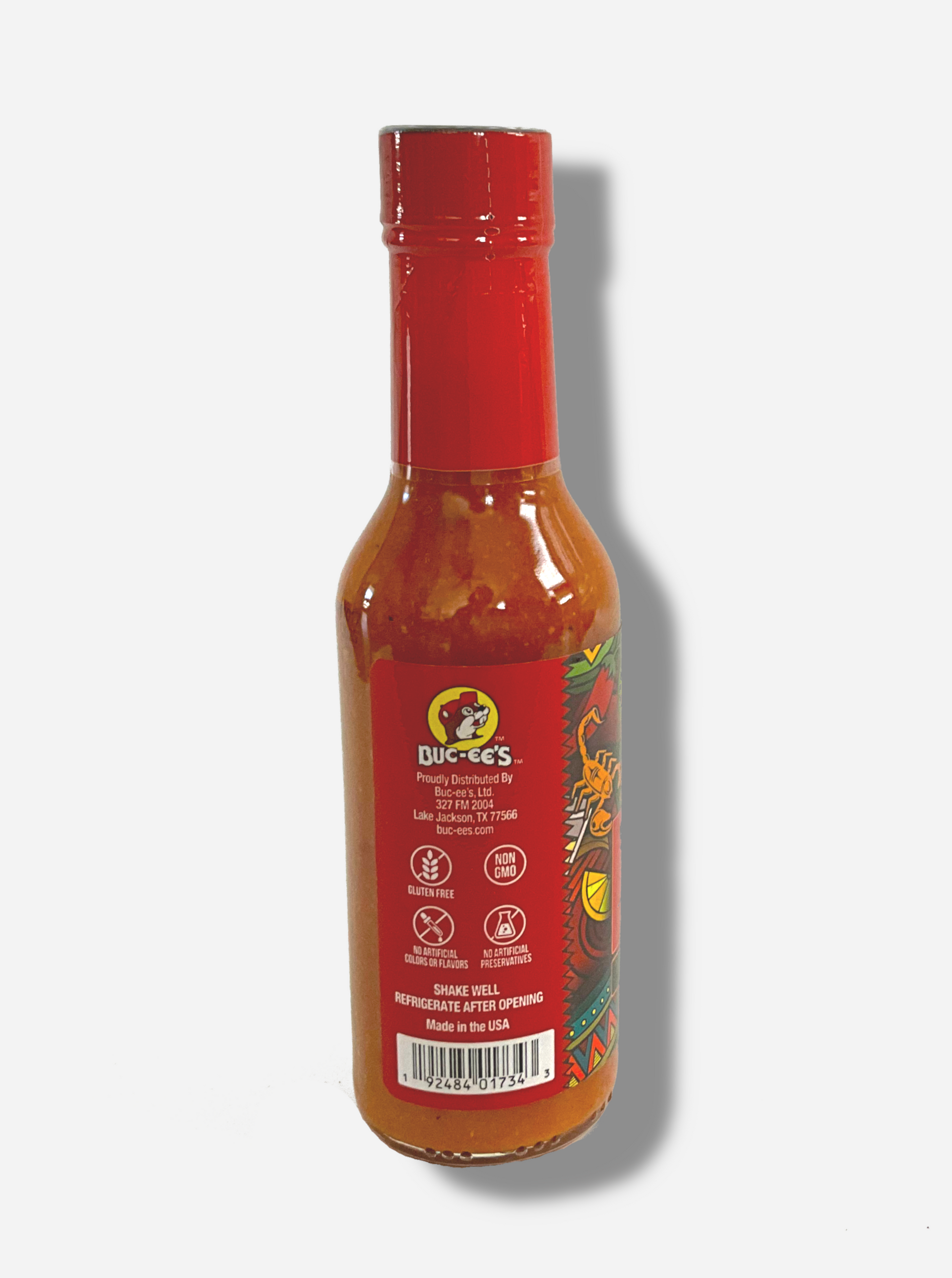 A picture of a small, tall bottle of hot sauce. The top of the bottle is sealed with a plastic top.  The back reads GLUTEN FREE, NON GMO, NO ARTIFICIAL COLORS OR FLAVORS, NO ARTIFICIAL PRESERVATIVES, then SHAKE WELL and REFRIGERATE AFTER OPENING.  Made in the USA.  The sauce inside is orange/red.