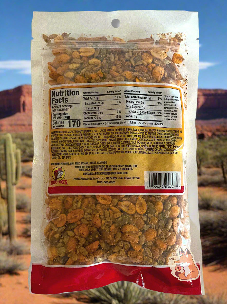 A picture of the back of bag of Buc-ee's Southwest trail mix.  The bag is clear plastic, At the bottom, after the ingredient listing, peanuts, sesame sticks, corn nuggets, sunflower seeds, and pumpkin seeds can be seen.  There appears to be a fair amount of spices on all the products.  The background is of a southwestern mesa, complete with cacti.