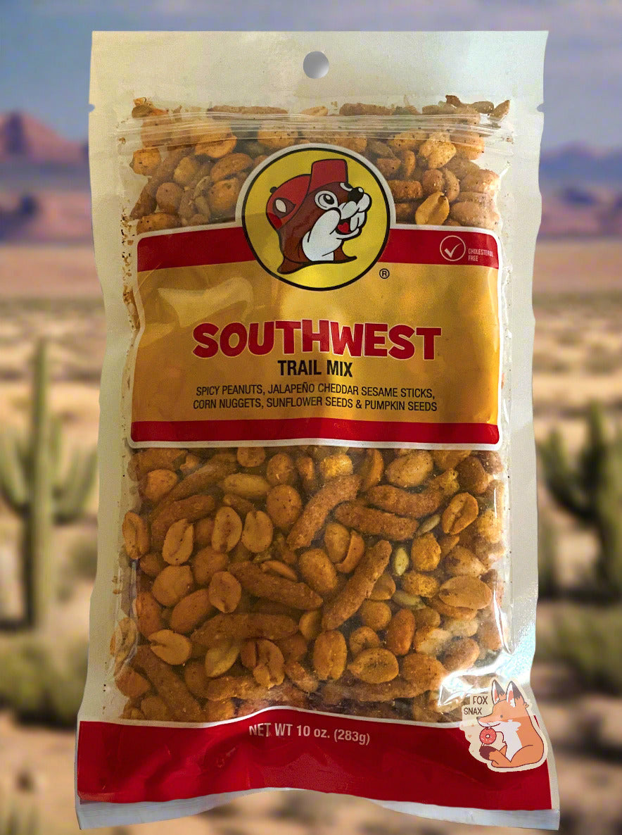 A picture of a bag of Buc-ee's Southwest trail mix.  The bag is clear plastic, and says SOUTHWEST TRAIL MIX on the front, with the iconic beaver logo wearing a red ball cap.  At the bottom, after the product listing, peanuts, sesame sticks, corn nuggets, sunflower seeds, and pumpkin seeds can be seen.  There appears to be a fair amount of spices on all the products.  The background is of a southwestern mesa, complete with cacti.