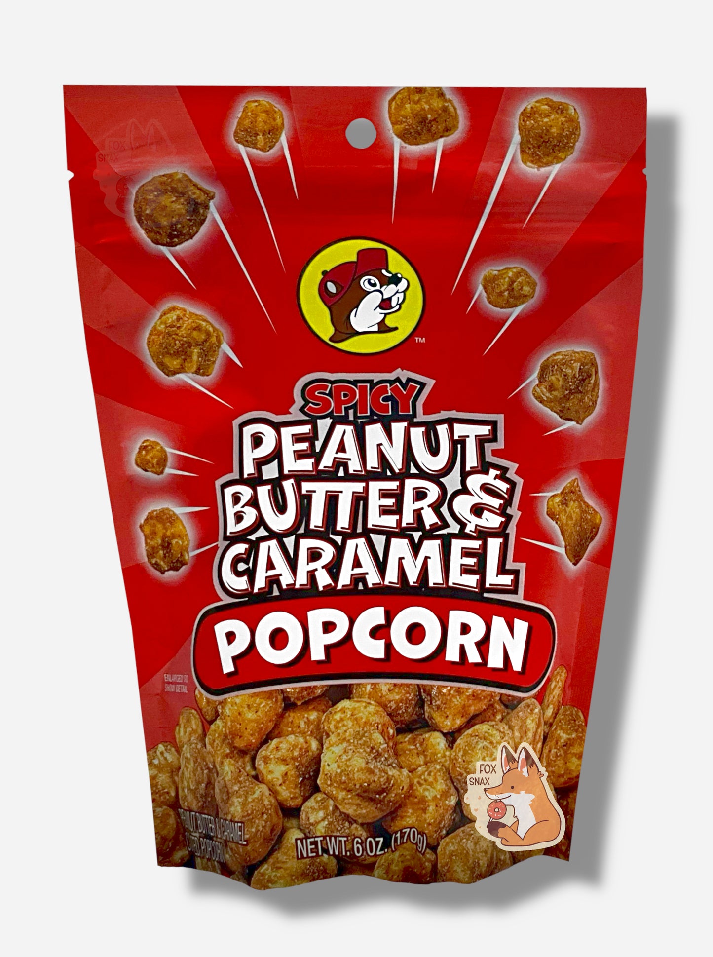 A picture of a red bag of Buc-ee's Spicy Peanut Butter & Caramel Popcorn. The front of the bag has a group of popcorn nuggets, each coated in brown peanut butter and caramel coating, exploding from the center. A pile of popcorn is on the bottom. The top center has the Buc-ee's logo, with cheerful beaver wearing a red ball cap, framed in a yellow circle, and reads SPICY PEANUT BUTTER & CARAMEL POPCORN.