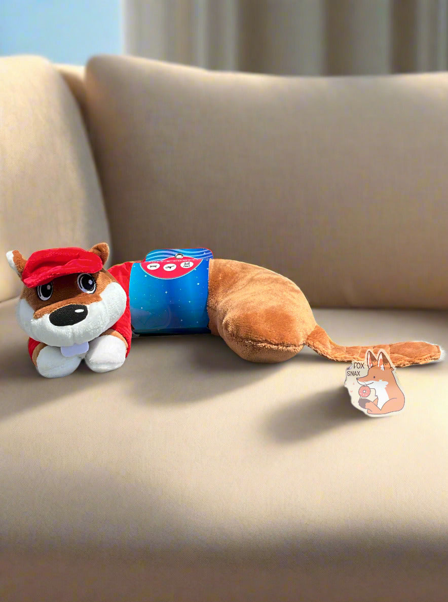 A picture of the side of a mostly u-shaped, travel pal pillow. It is is shaped roughly like Buc-ee the Beaver. Buc-ee is wearing a red ball cap, a red Buc-ee's shirt complete with Buc-ee logo, and sports a brown beaver tail. A dark blue paper label is shown around his midsection. The pillow is sitting on a tan soft couch in a living room.