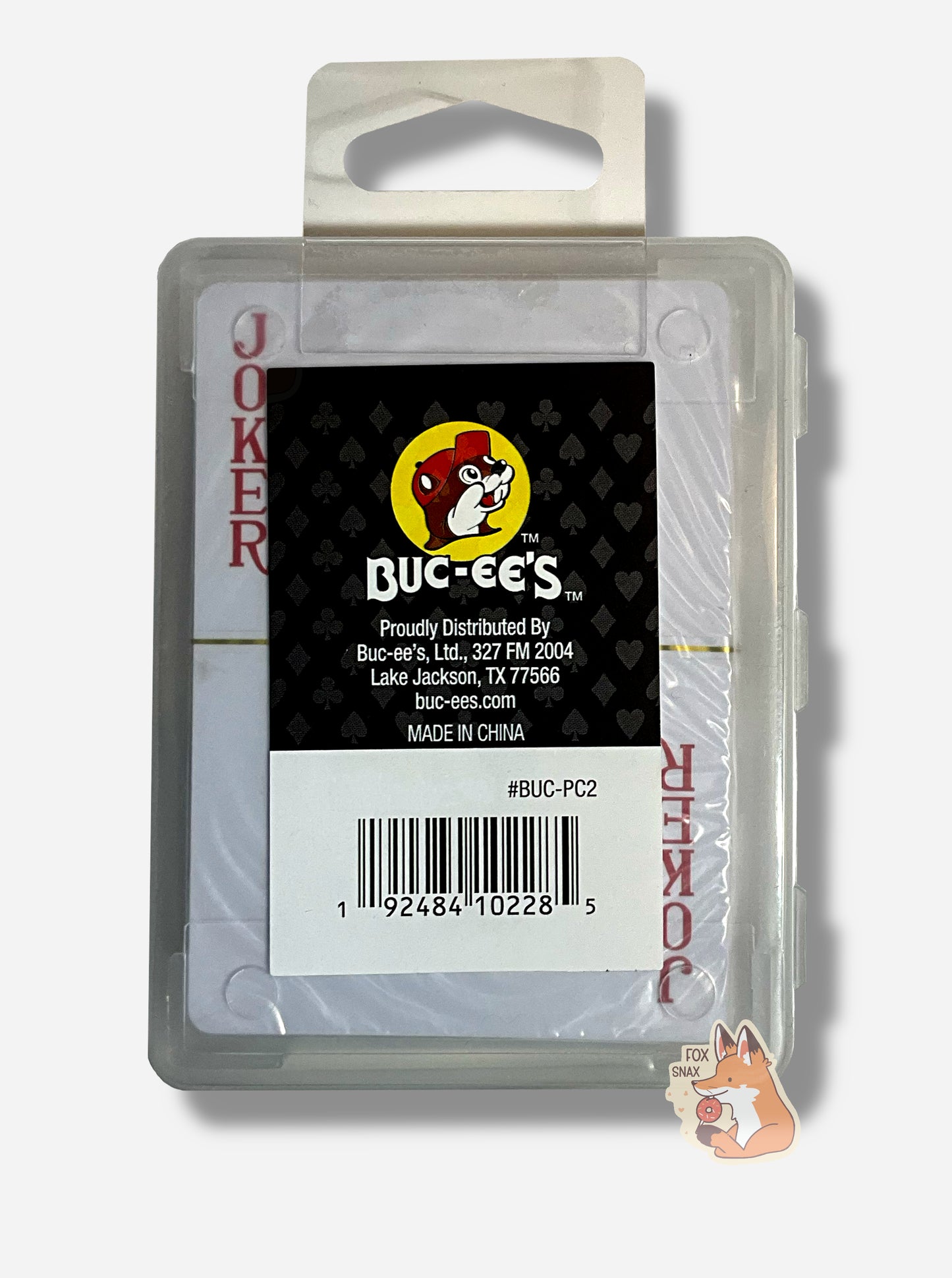 A picture of the back of a pack of Buc-ee's Waterproof Playing Cards. The pack is plastic, rectangular, and clear. A joker card can be seen through the plastic. A small rectangular sticker with the Buc-ee's logo against a hearts/spades/diamonds/clubs background can be seen.