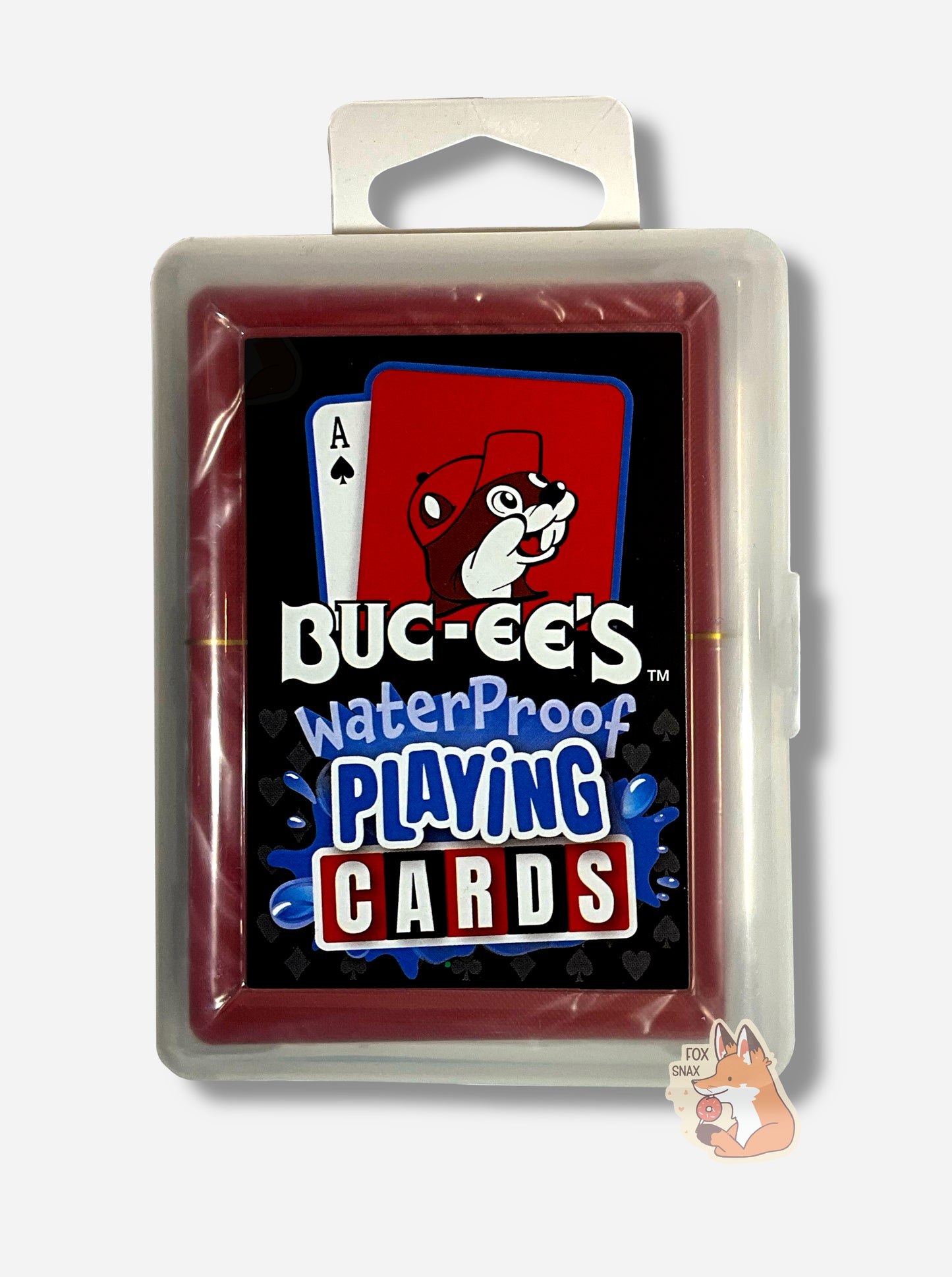 A picture of a pack of Buc-ee's Waterproof Playing Cards. The pack is plastic, rectangular, and clear. The front of the pack has two cards at the top - the first the ace of spades, the second a picture of Buc-ee the Beaver against a red background. Underneath the cards reads: BUC-EE'S WATERPROOF PLAYING CARDS, each word in a different font. The words PLAYING CARDS are surrounded by splashing blue water.