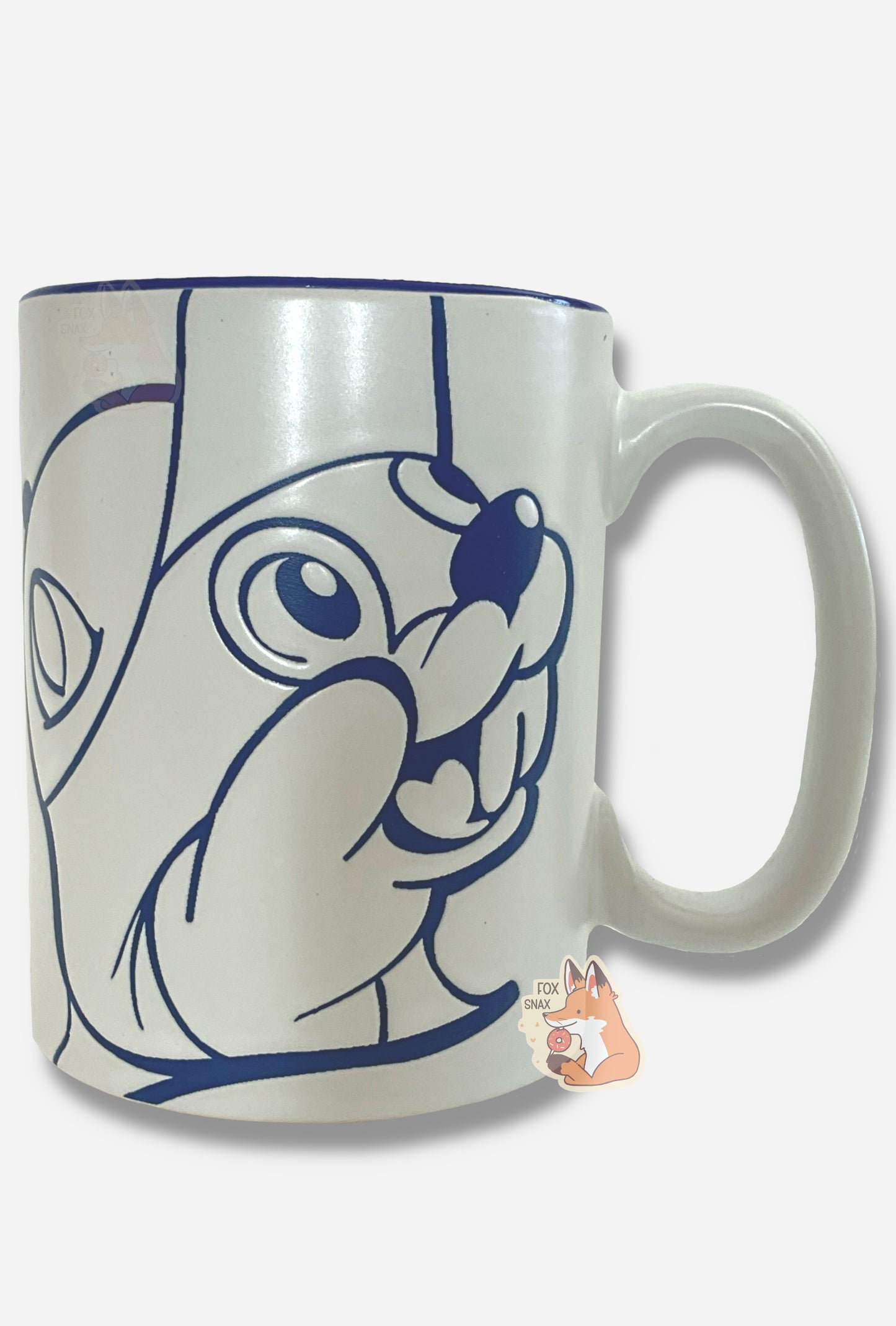A picture of a ceramic, dark blue and white coffee mug. The mug prominently features a picture of Buc-ee The Beaver on the front and back, in dark blue. The interior of the mug is a dark blue as well, and rest of the mug is white.