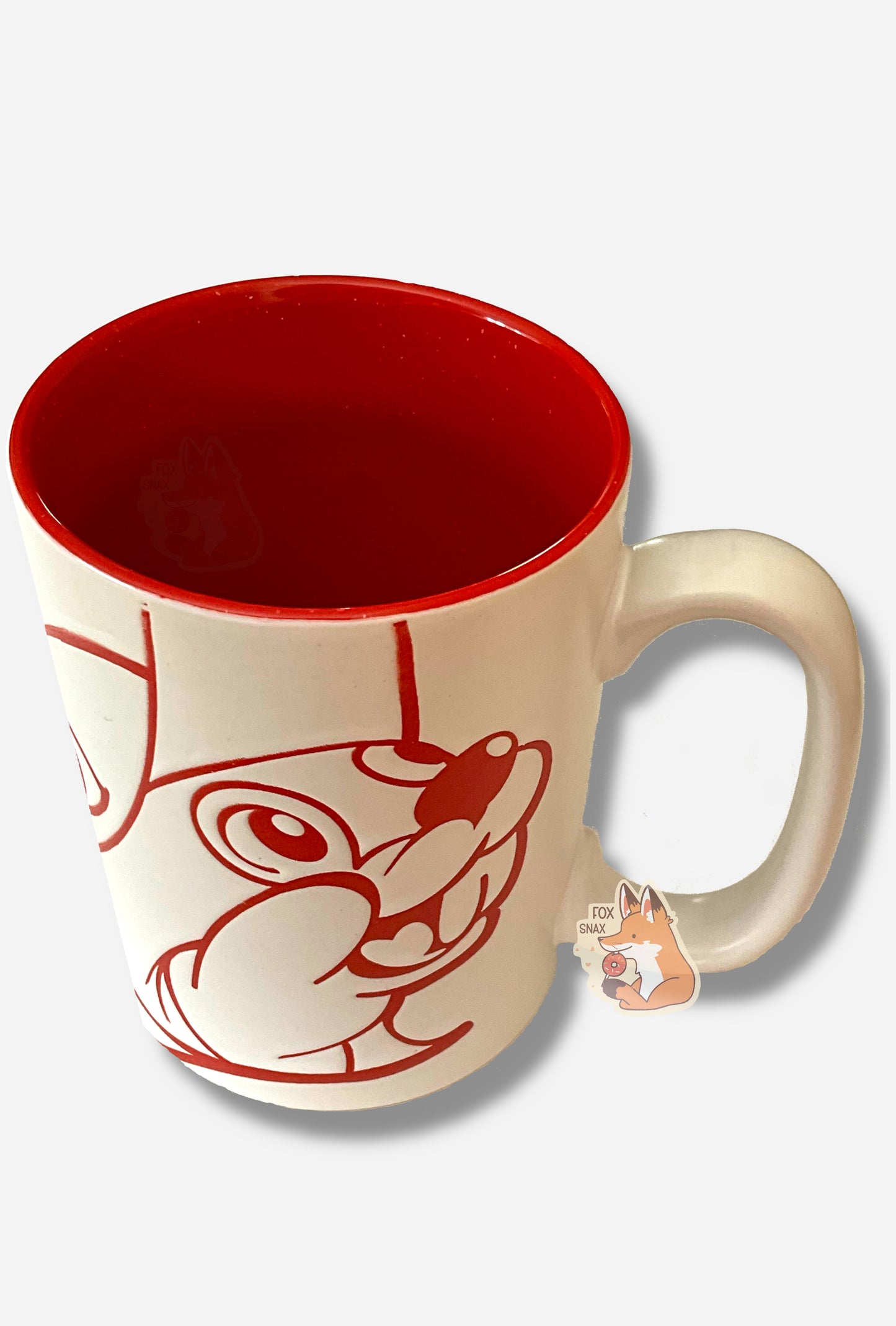A picture of a ceramic, red and white coffee mug. The mug prominently features a picture of Buc-ee The Beaver on the front and back, in red. The interior of the mug is a bright red as well, and rest of the mug is white.
