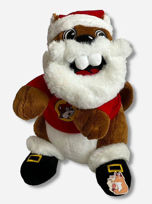 A picture of a wide-eyed Buc-ee The Beaver Plush.  Buc-ee is wearing a red Buc-ee's shirt with logo, black Santa boots, with square gold buckle, a red Santa hat, and a giant white Santa beard.  His buck teeth poke out from his mouth in a cute grin.