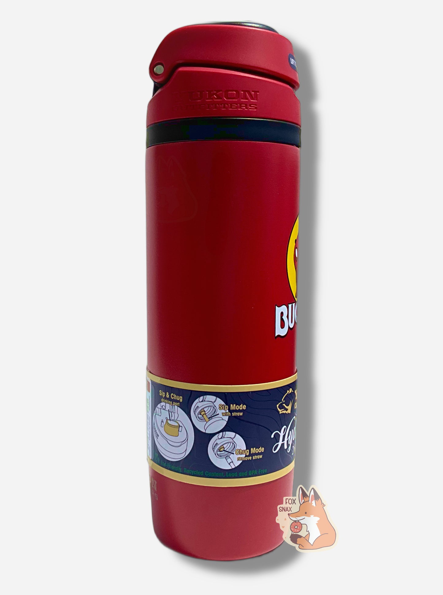 A picture of the side of a tall red cylindrical water bottle.  Part of the big picture of Buc-ee The Beaver on it can be seen.  The surface is smooth and red, as it is red paint covering stainless steel.  The small plastic handle is closed. The top is black and red plastic, and is closed.  A paper wrapper around the bottom reads: Sip & Chug drinking port, then Sip Mode With Straw, then Cug Mode Remove Straw.