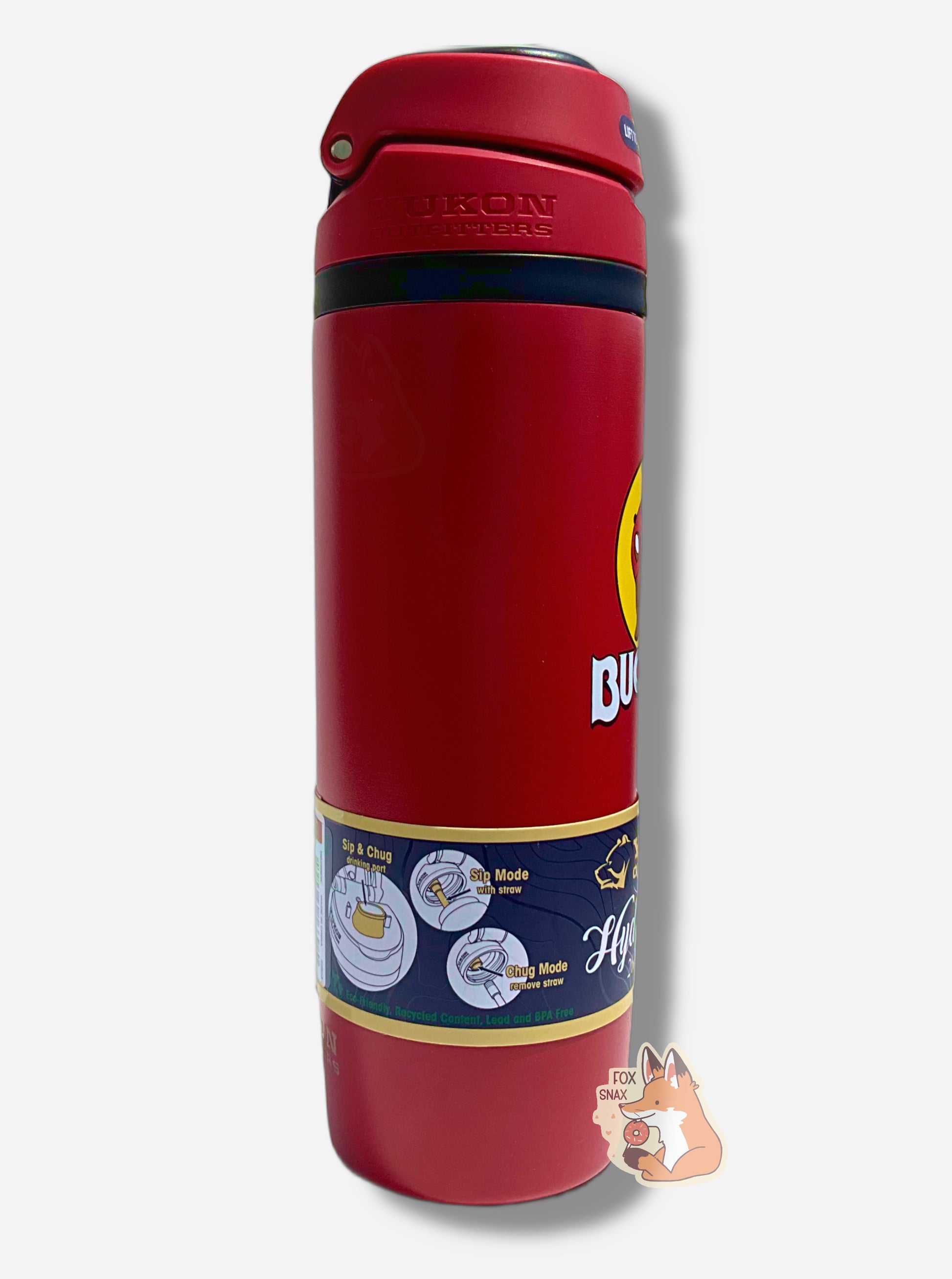 A picture of the side of a tall red cylindrical water bottle.  Part of the big picture of Buc-ee The Beaver on it can be seen.  The surface is smooth and red, as it is red paint covering stainless steel.  The small plastic handle is closed. The top is black and red plastic, and is closed.  A paper wrapper around the bottom reads: Sip & Chug drinking port, then Sip Mode With Straw, then Cug Mode Remove Straw.