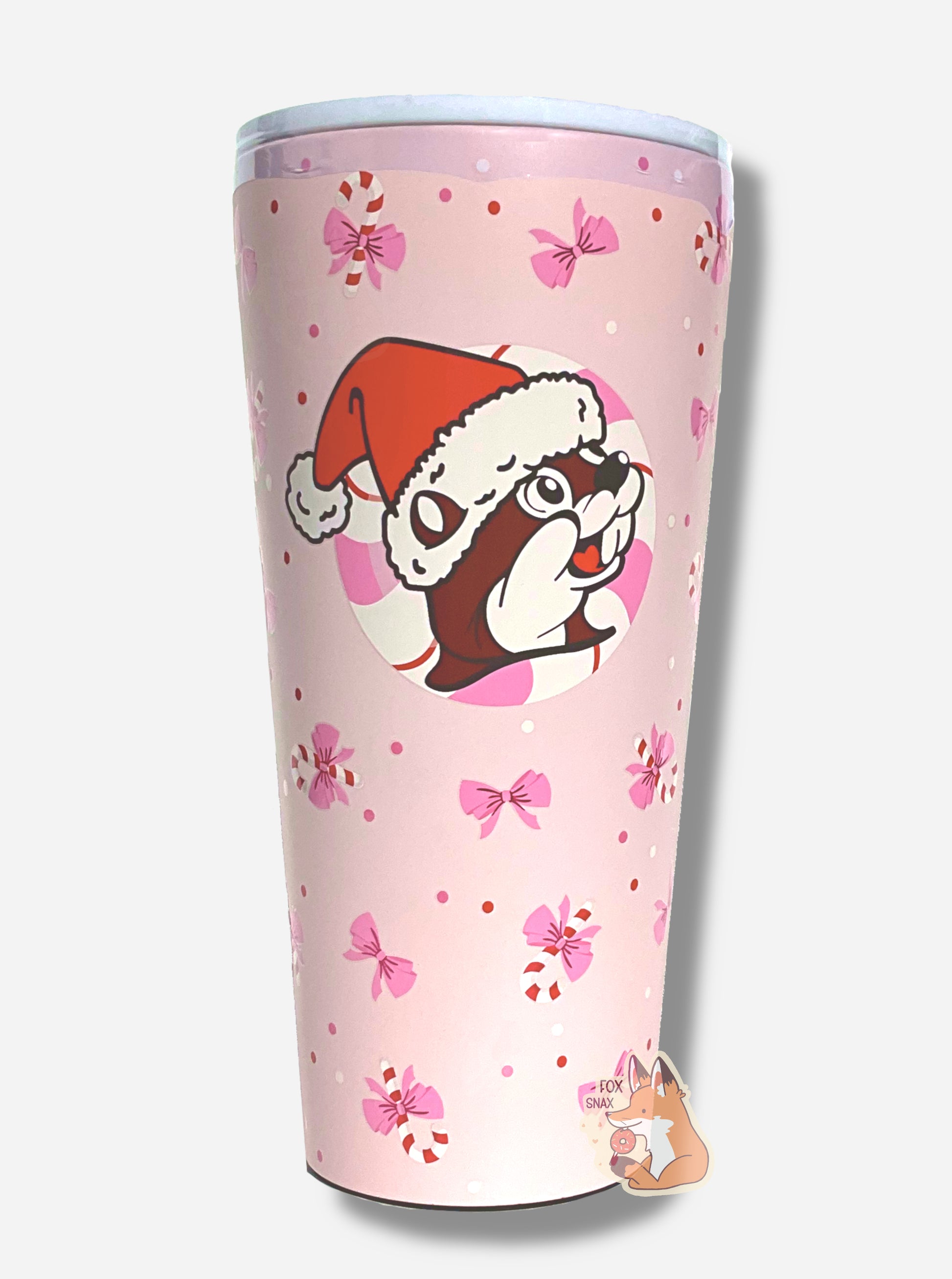 A picture of a pink double pint tumbler, with a light pink background full of bows and candy canes.  The middle of the tumbler has the Buc-ee's logo, but with Buc-ee The Beaver wearing a Santa hat, framed against a red and white peppermint.  The top of the tumbler is white, with a pink slide for different beverage dispenser amounts.  