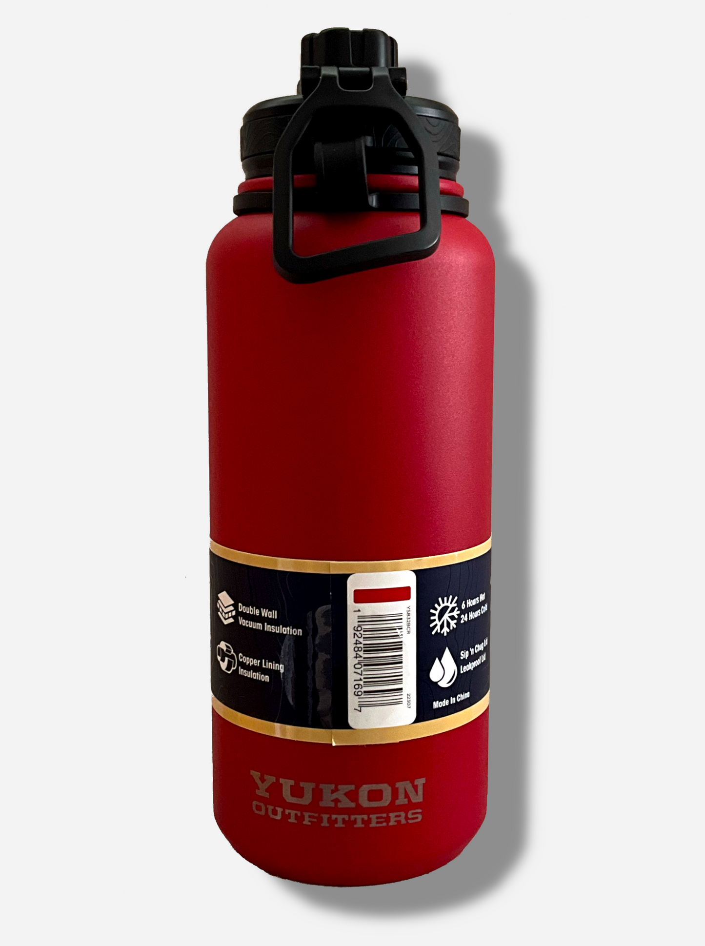 A picture of the back of a tall red cylindrical water bottle.  The surface is smooth and red, as it is red paint covering stainless steel.  There is no handle.  The top is a screw on plastic knob with a keychain handle.  Underneath the paper label, engraved text on the bottom reads: YUKON OUTFITTERS.