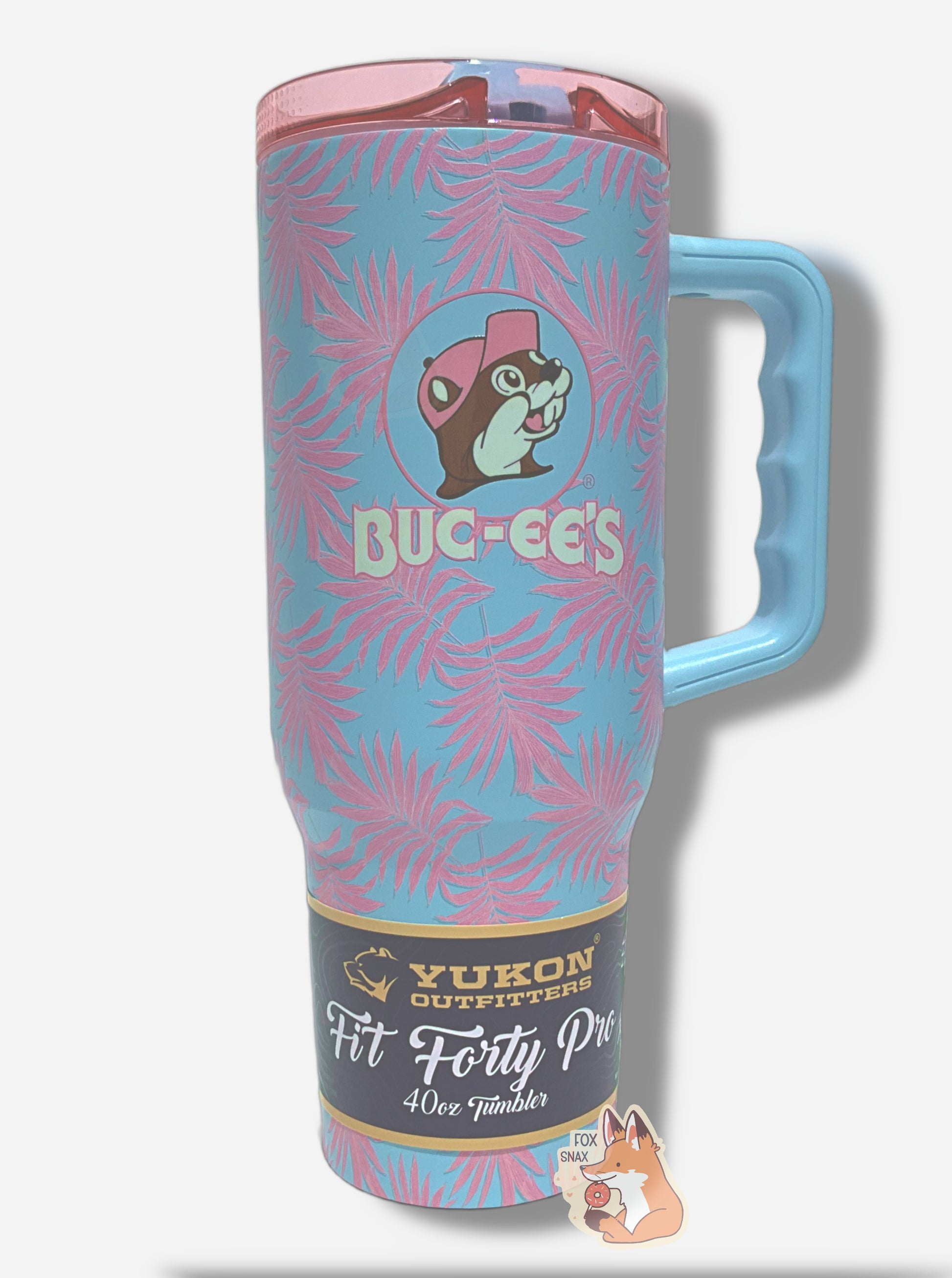 A picture of a tall, light blue, sorta skinny tumbler, with a big picture of Buc-ee The Beaver on it.  Buc-ee's hat, and the circle behind him, is in light pink.  The surface is light blue, and covered in light pink palm fronds.  It is matte paint in covering stainless steel.  The handle and sipper on top of the lid are light blue.  The top is light transparent pink plastic.  A paper wrapper around the bottom reads: Yukon Outfitters.  Fit Forty Pro 40 oz Tumbler.